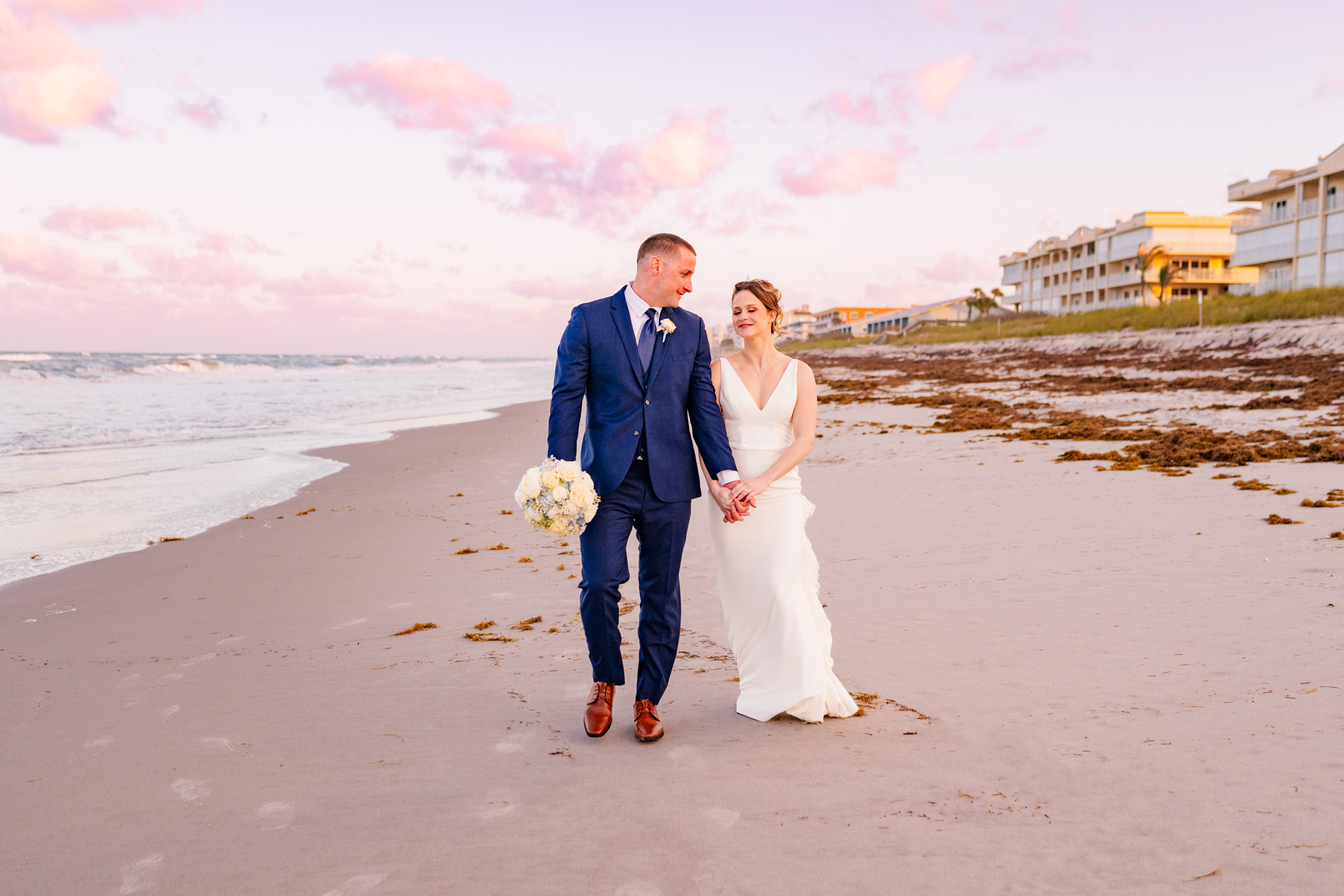Bride and groom walking along the oceanfront after their wedding ceremony.