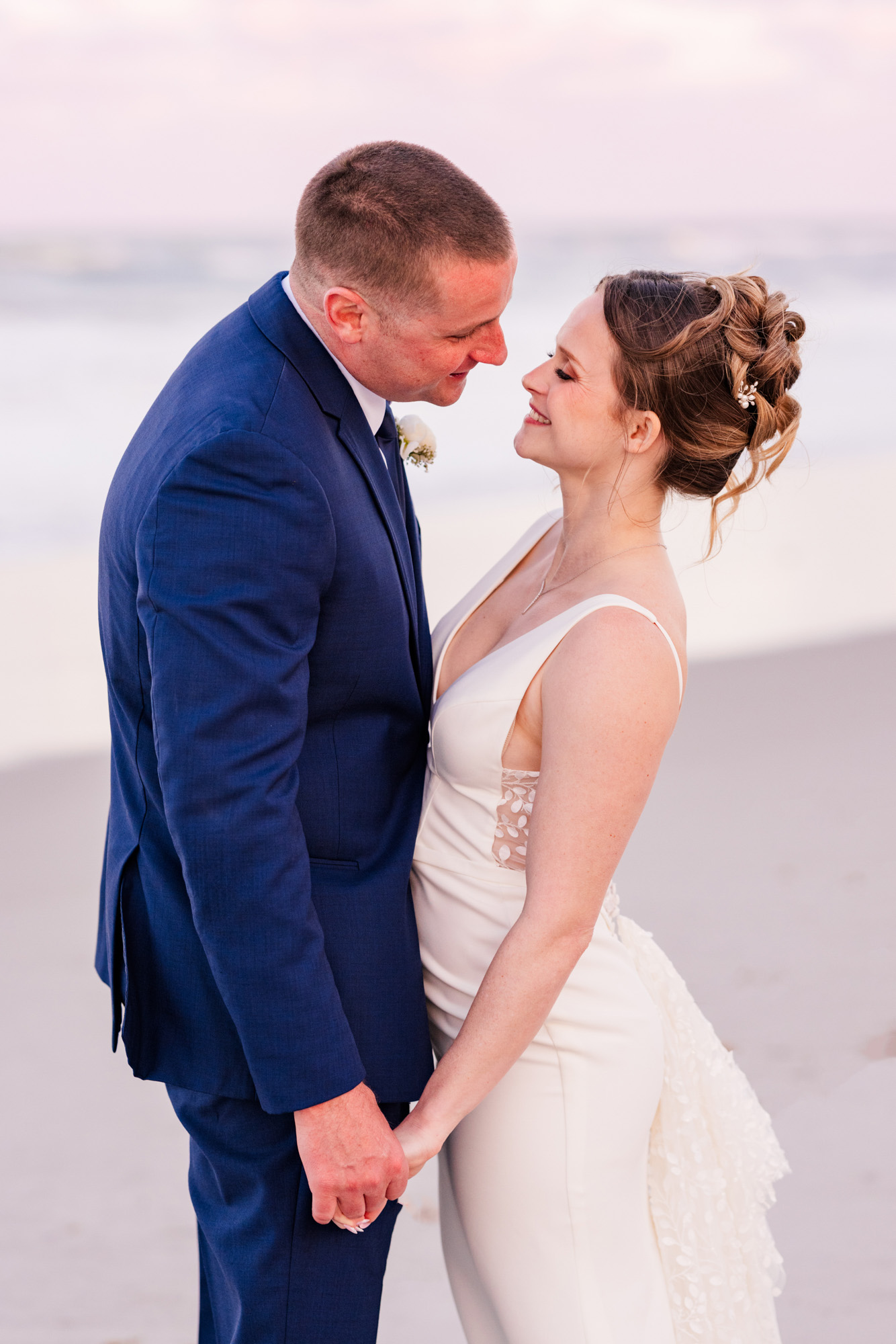 Close romantic portrait of the bride and groom smiling at each other on the beach.