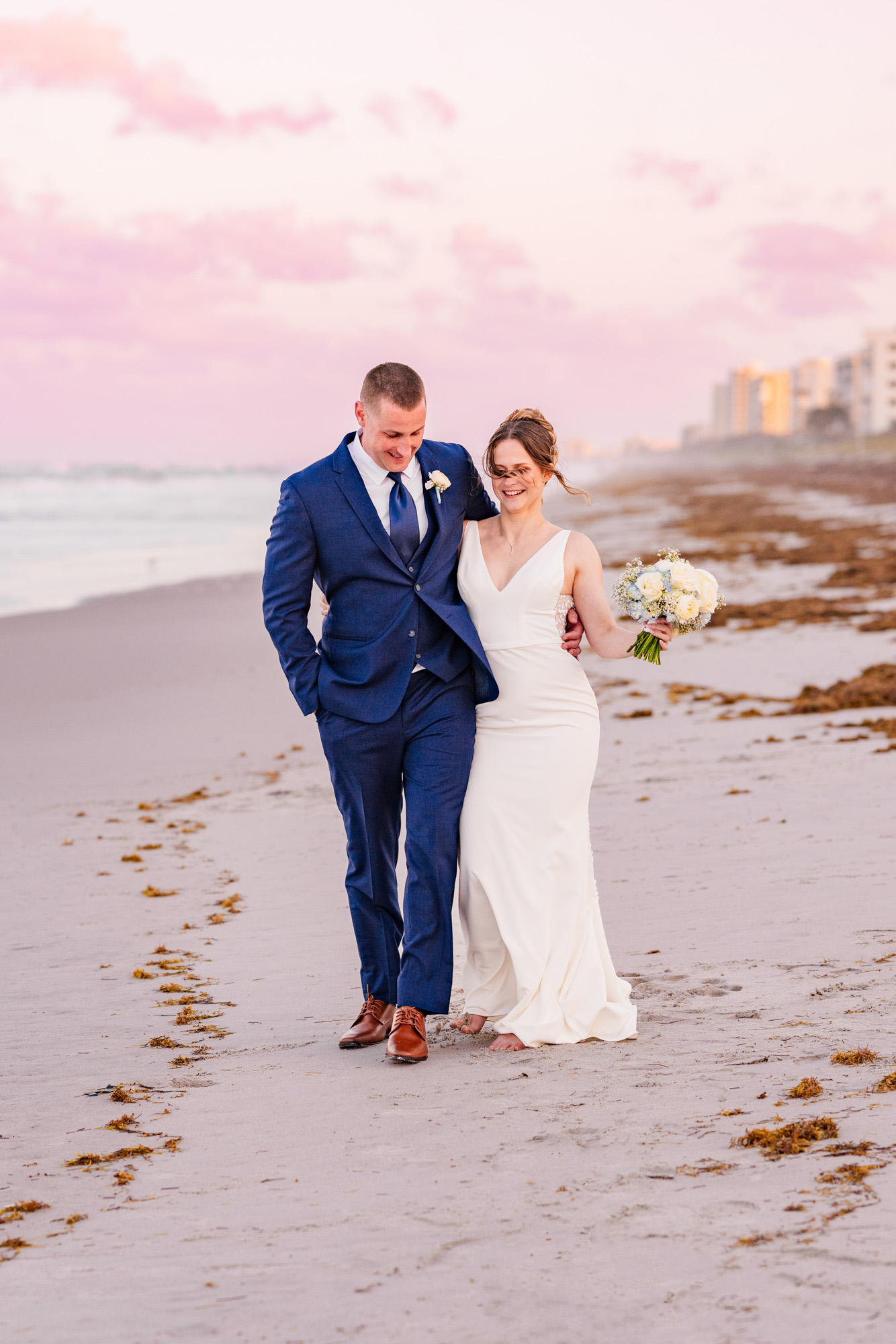 Bride and groom strolling together on the beach at sunset near Harbour House Oceanfront.
