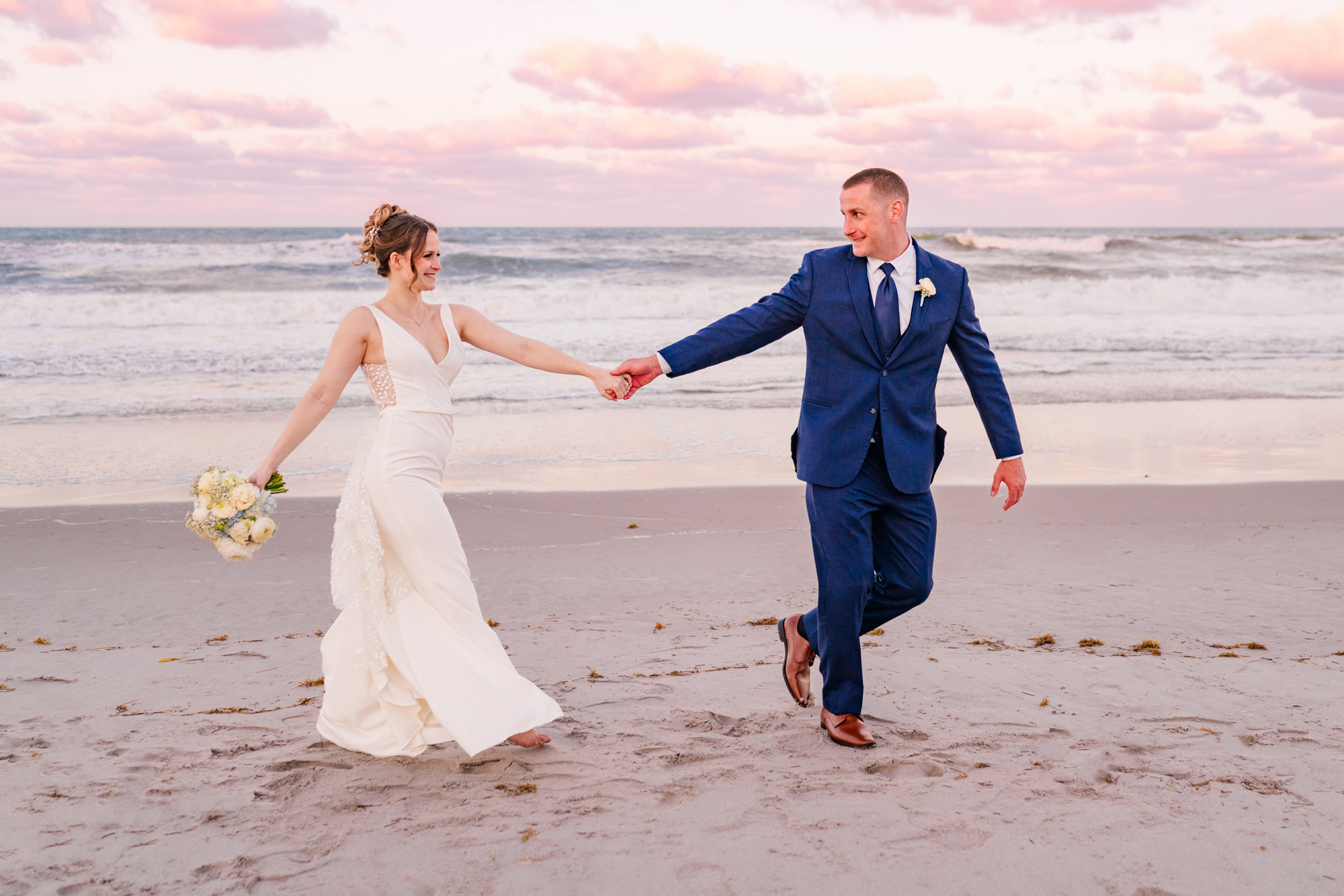 Bride and groom walking arm in arm along the beach after their wedding.