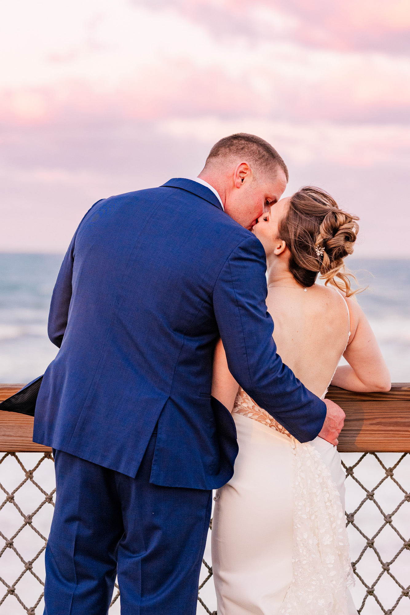 Newlyweds celebrating on the boardwalk with the bride holding her bouquet overhead.