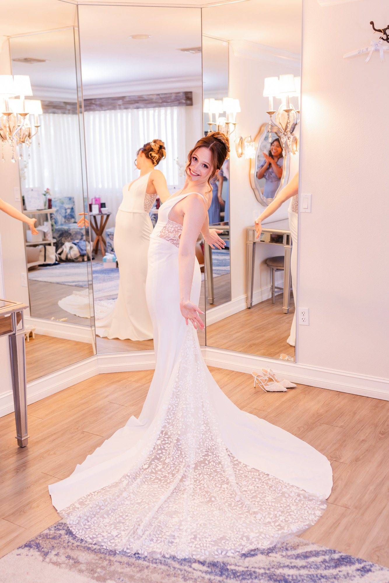 Bride posing in her fitted white wedding dress in front of mirrored walls.