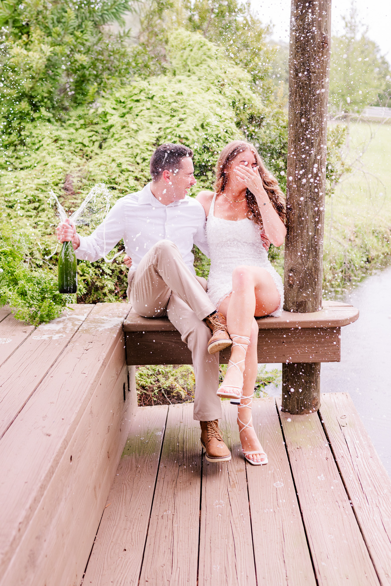 cople laughing while popping champagne