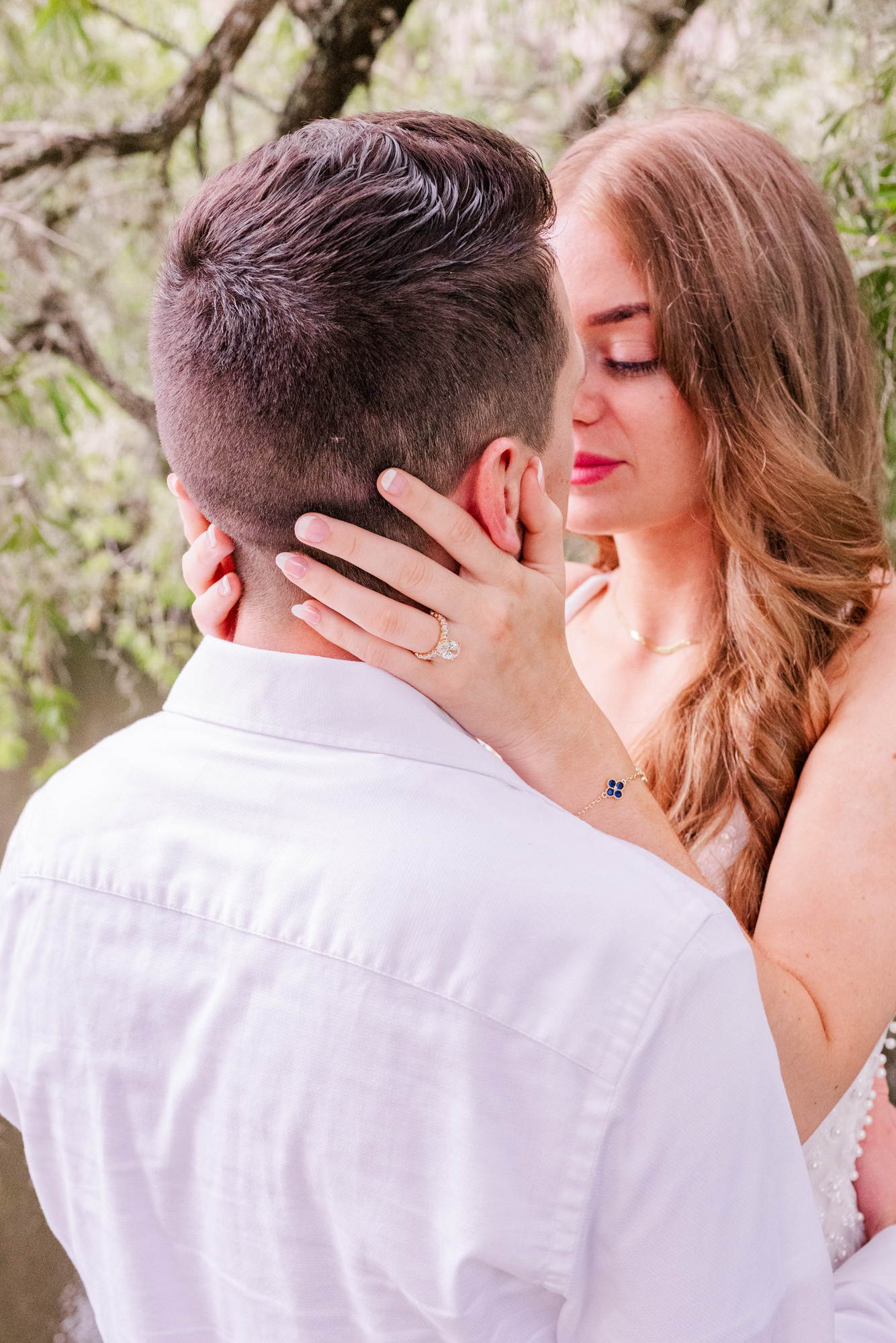 woman holding head of man with view of engagement ring