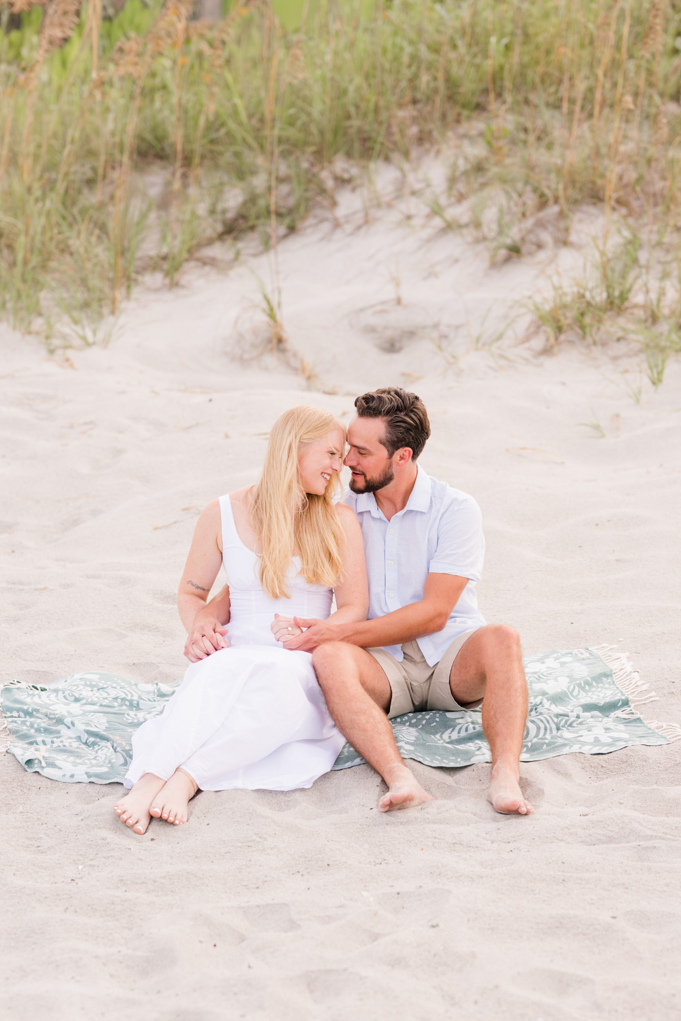 Man kissing woman's head while sitting on the dunes
