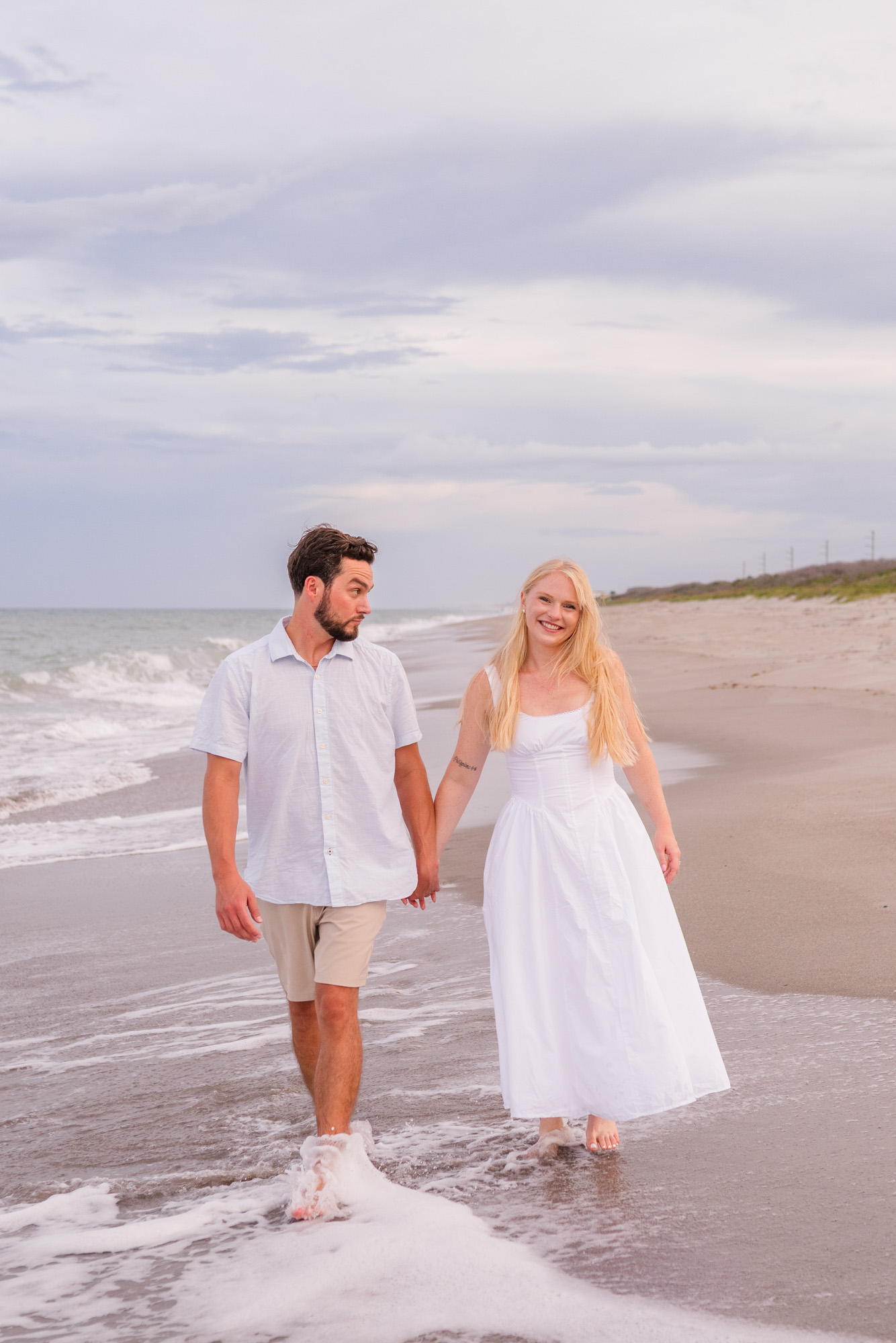 couple holding hands and walking in the water