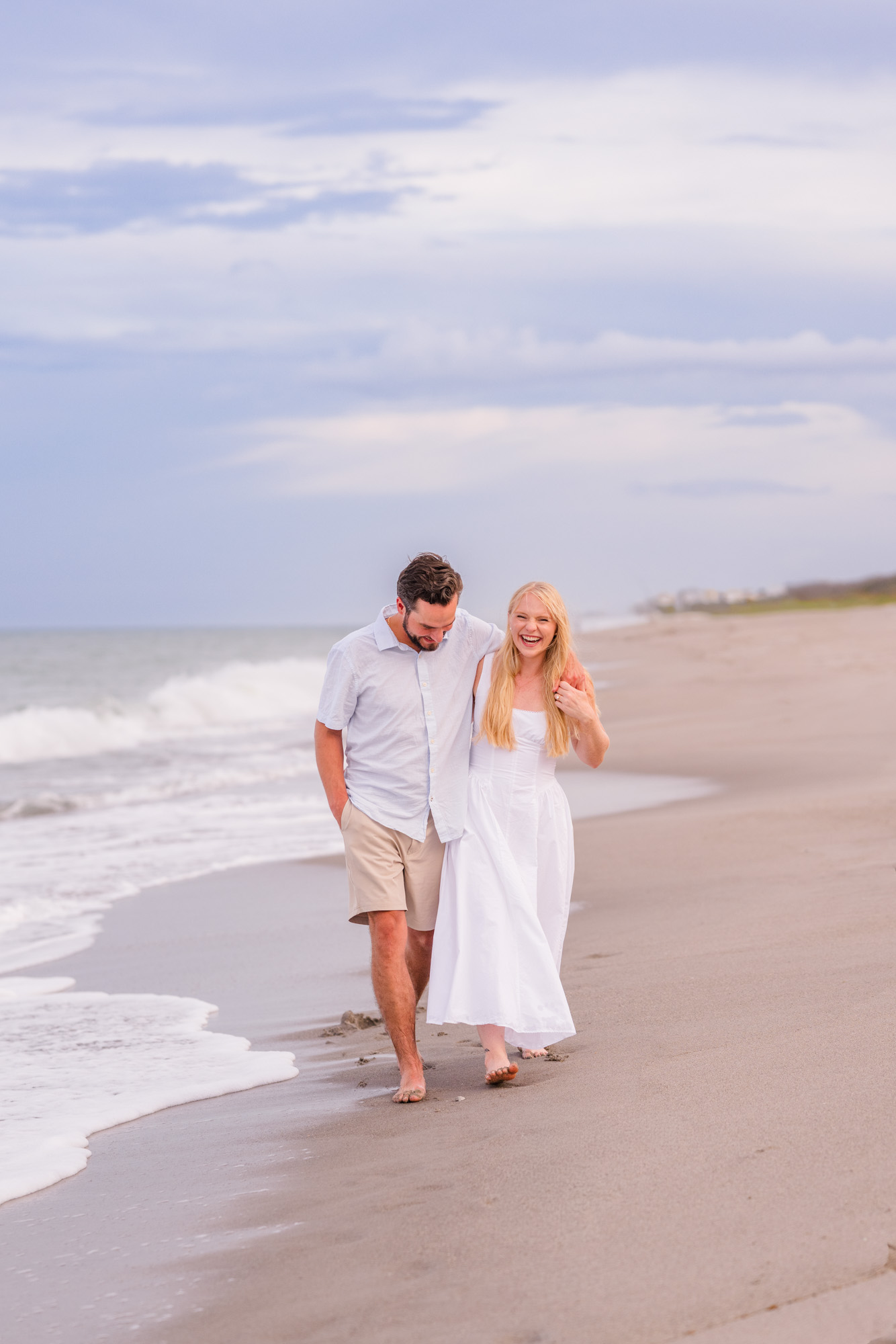 couple holding hands and walking in the water during their beach engagement session