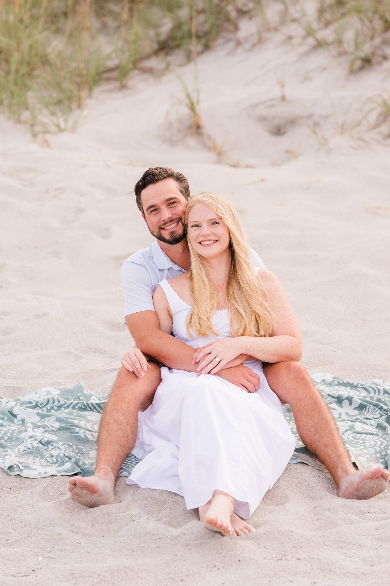 couple sitting on the sand hugging on Melbourne Beach