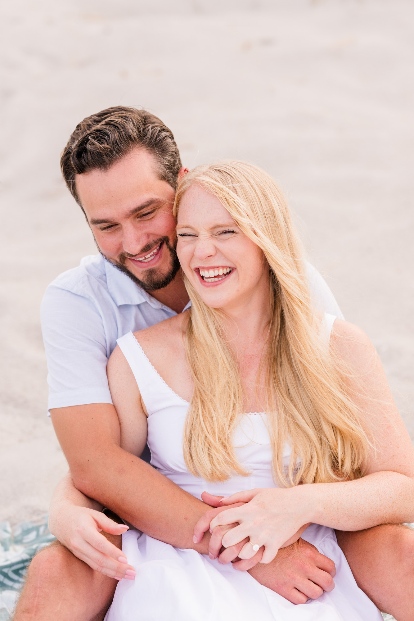 Man making woman laugh while sitting on the dunes