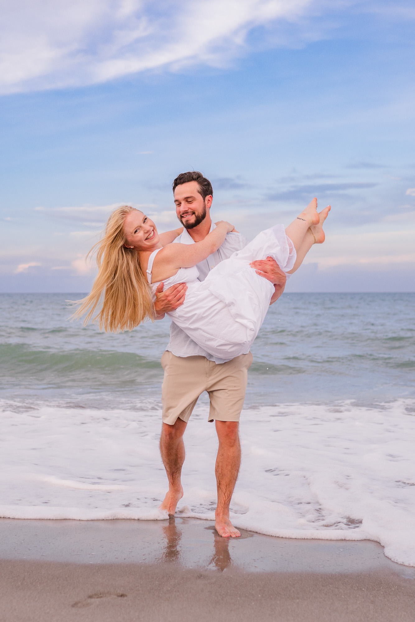 Man holding woman in his arms during their Melbourne Beach engagement session