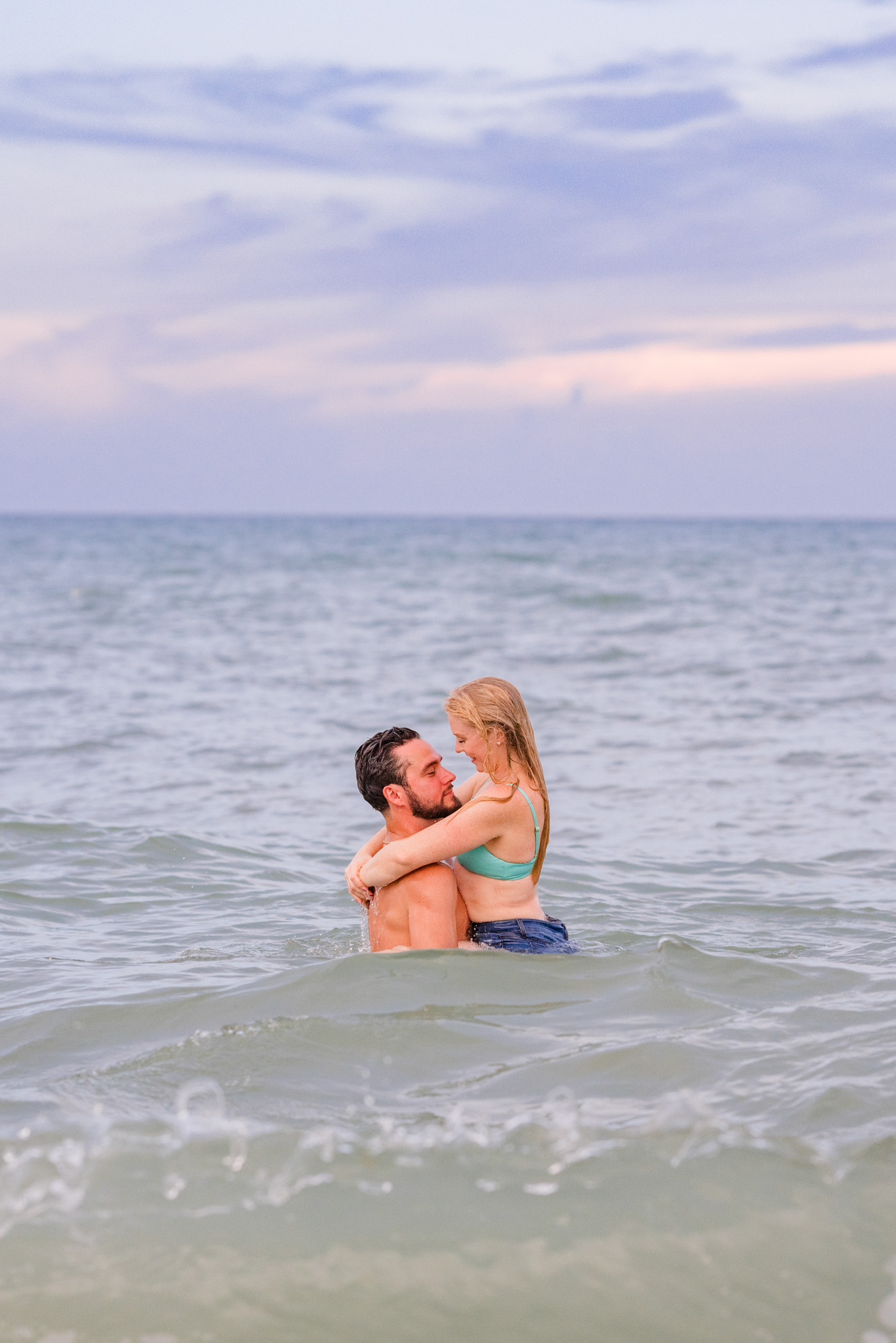 Woman holding onto man during their Melbourne Beach engagement session
