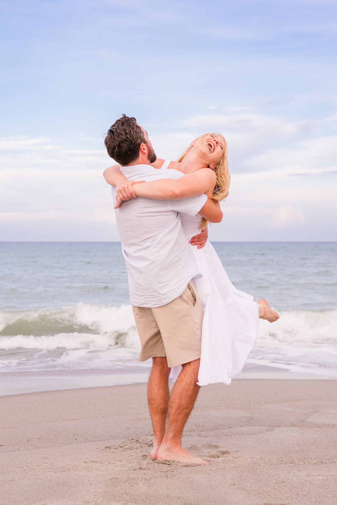man spinning woman in white dress on Melbourne Beach
