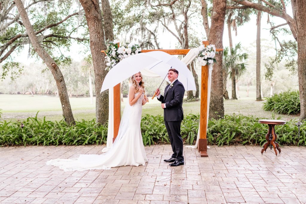 A couple holding umbrellas while saying vows at elopement at Up the Creek Farms
