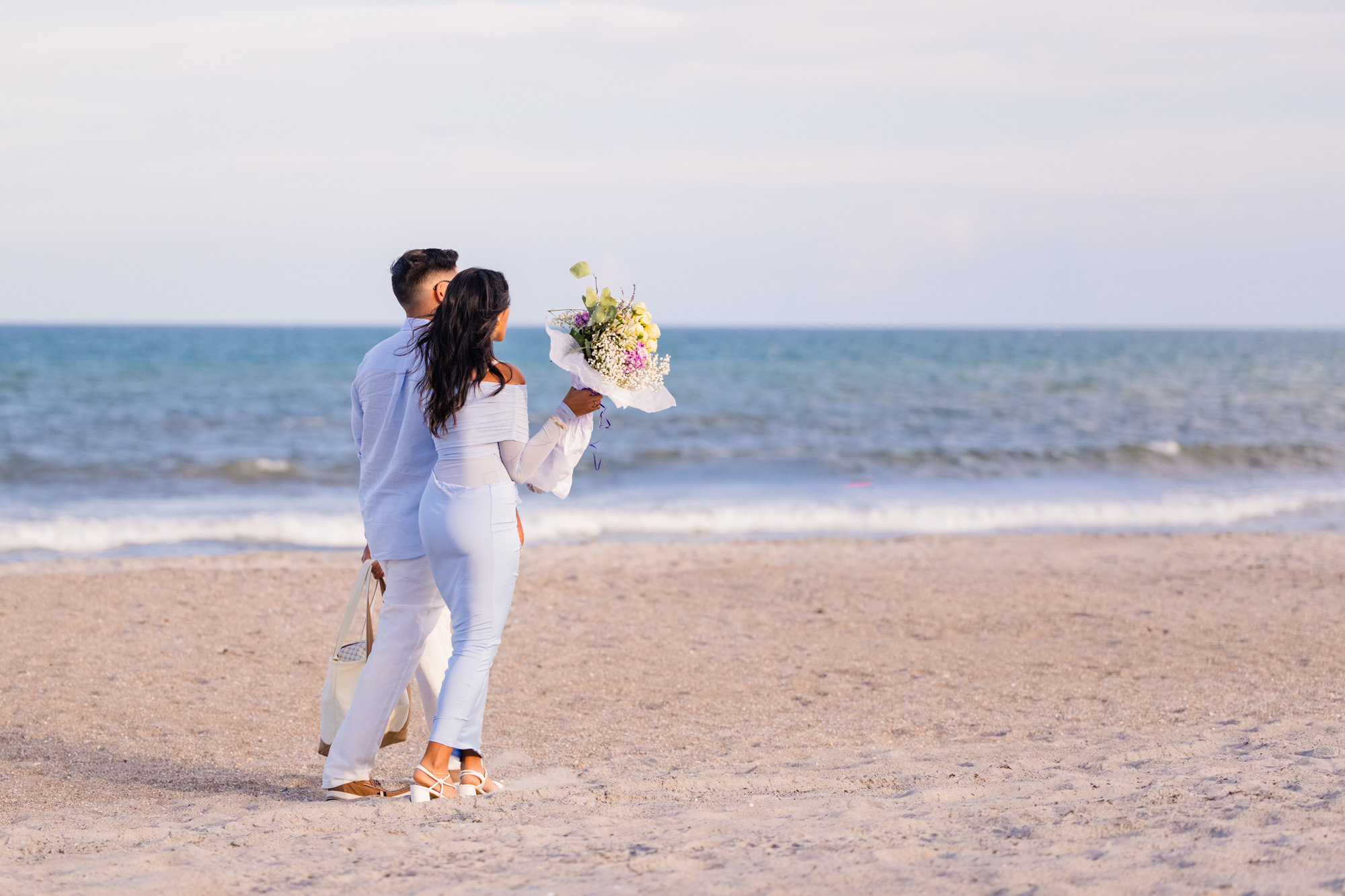Man and woman walking down beach to wear the man is going to propose on Cocoa Beach, Florida