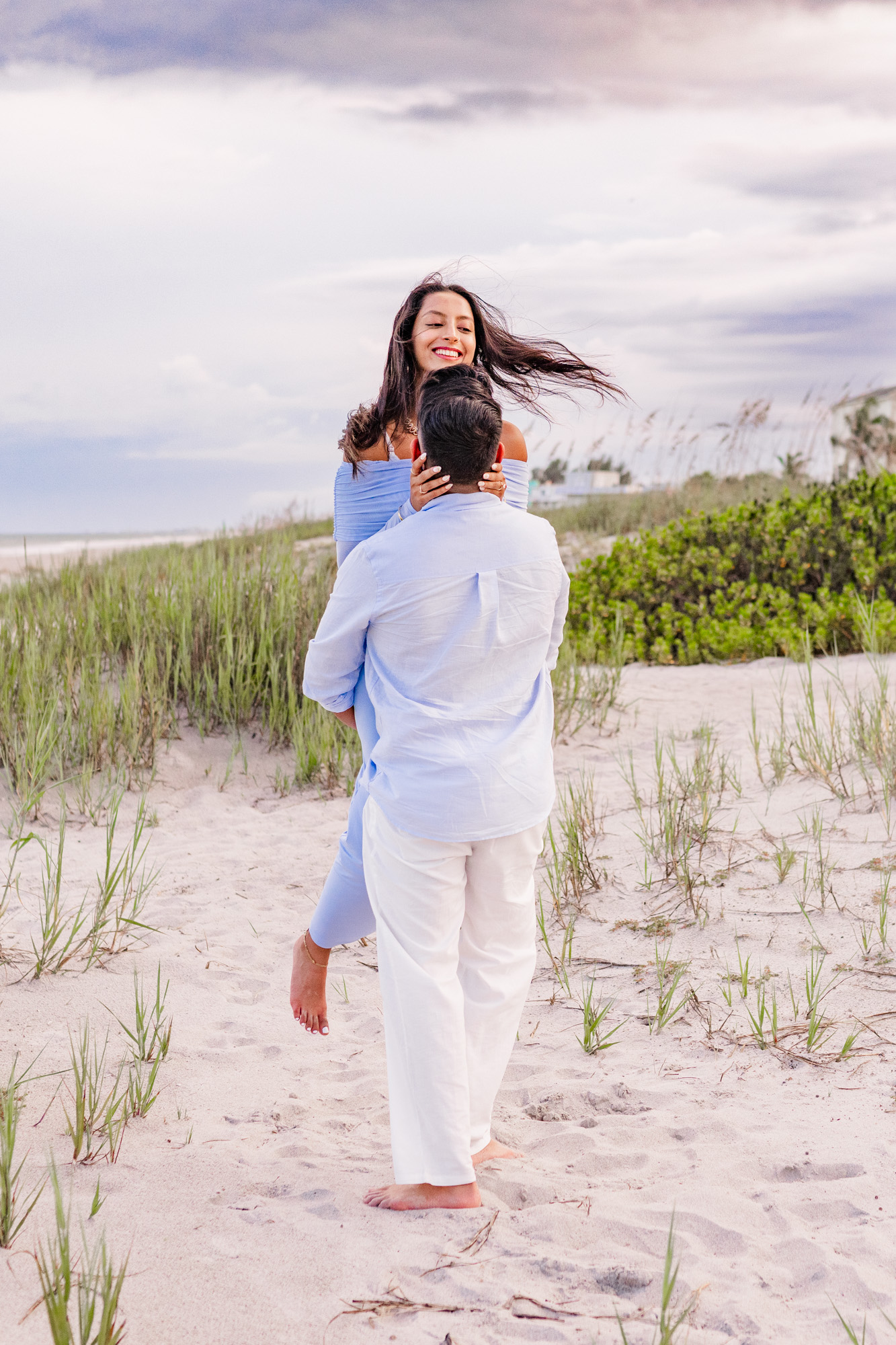 Man picking up and spinning woman on Cocoa Beach Florida after he got engaged