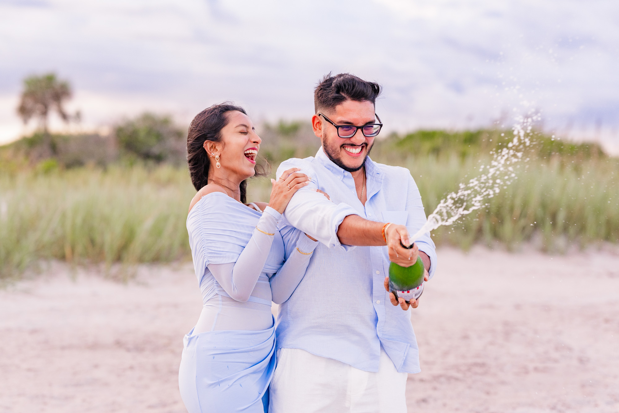 Man popping champagne and it sprays on Cocoa Beach