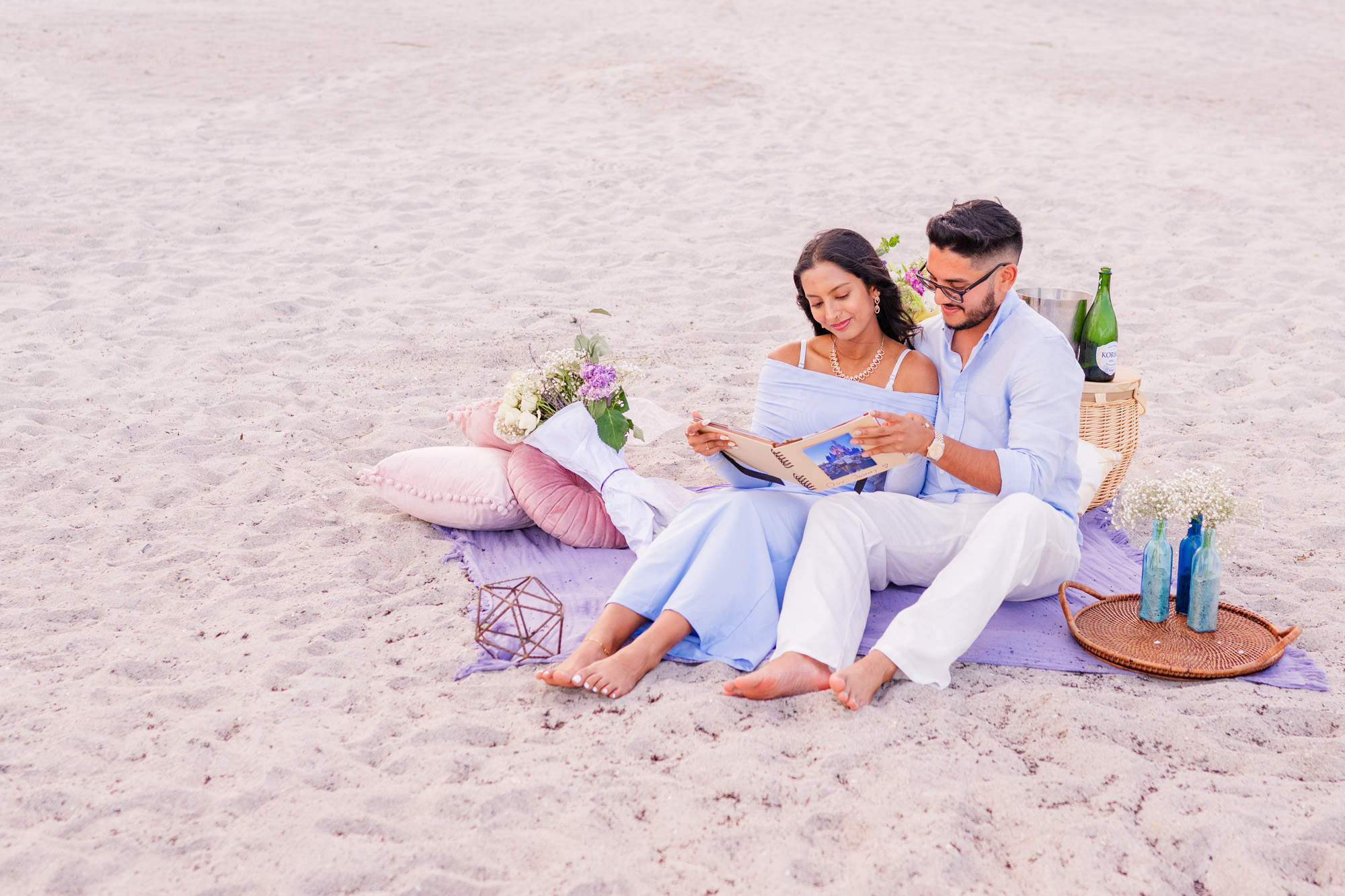 Couple sitting on a lavender blanket looking at a photo album that the man made for her