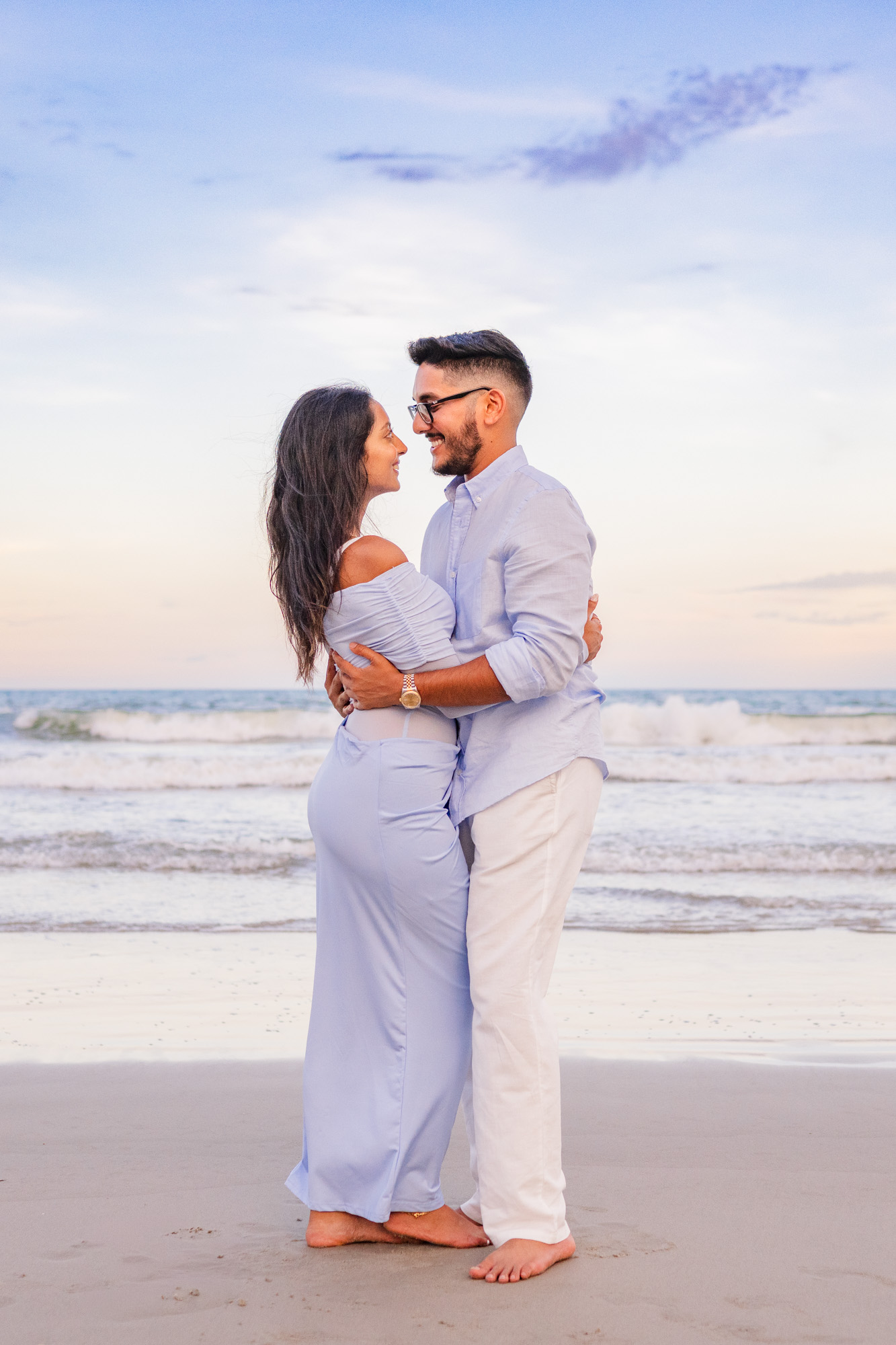 man and woman hug while the sky turns soft blues and oranges on Cocoa Beach