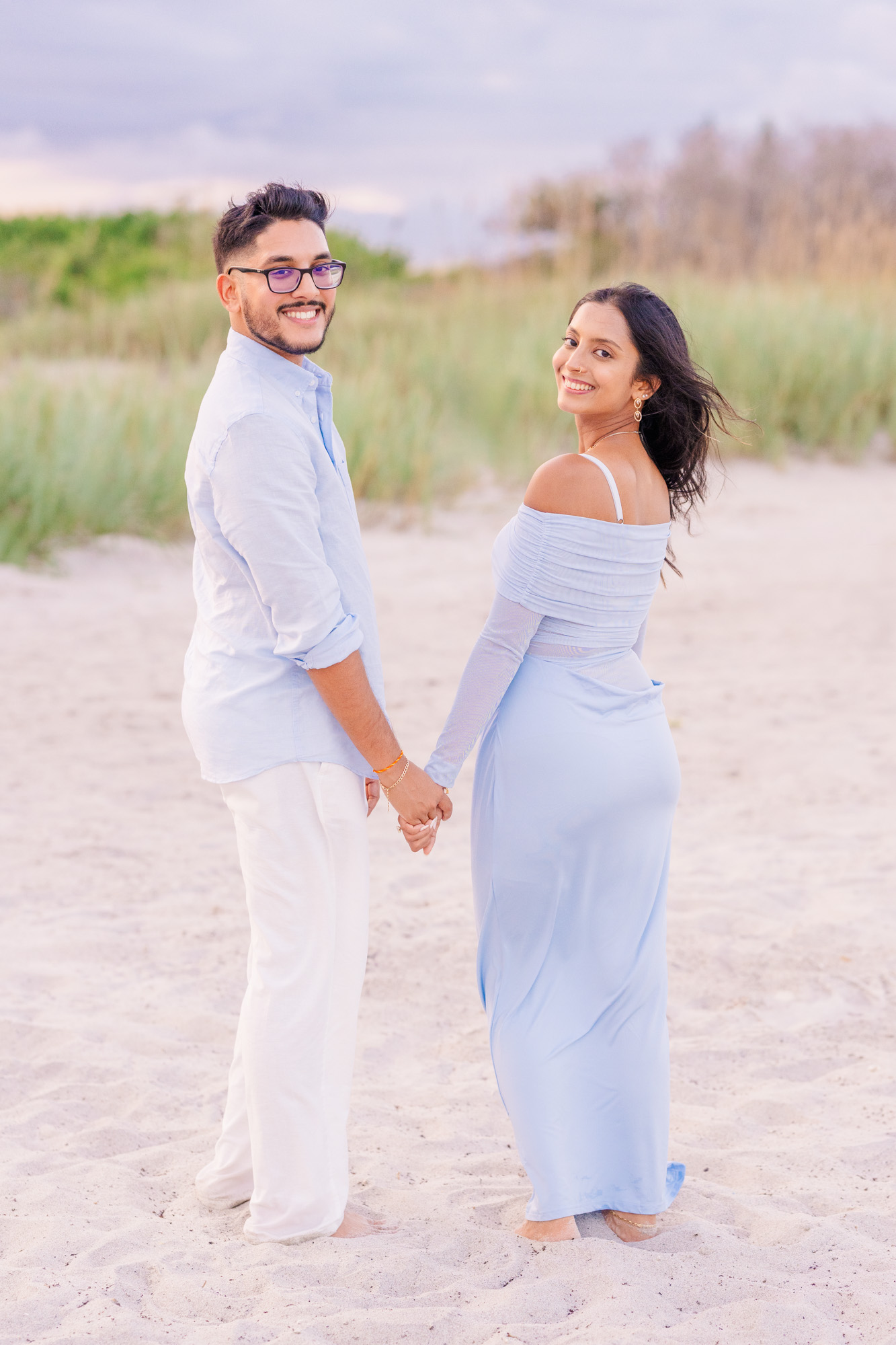 man and woman in blue look over their shoulders while on Cocoa Beach