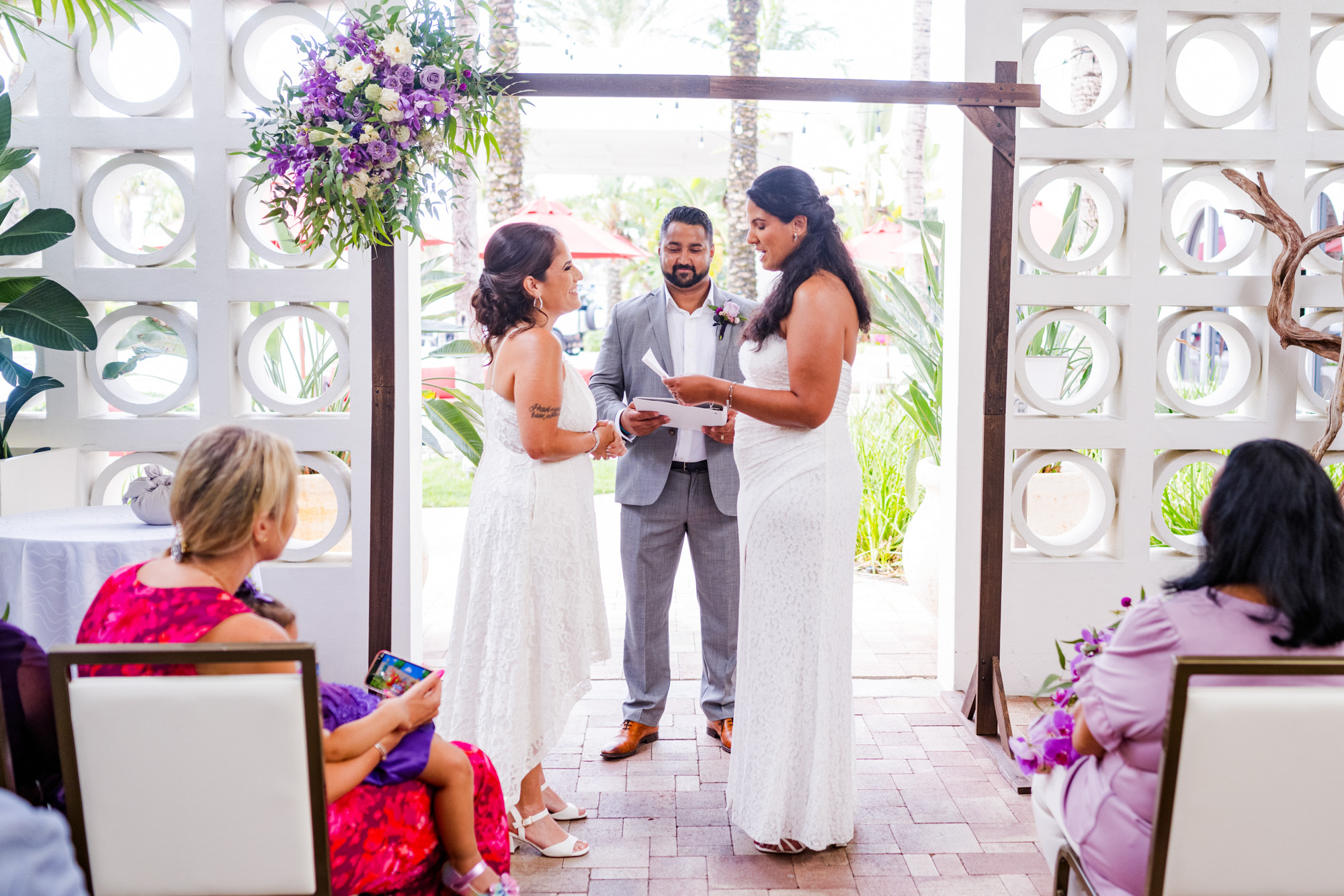 Wedding ceremony at Costa d’Este in Vero Beach with a floral arch and modern white architectural backdrop.