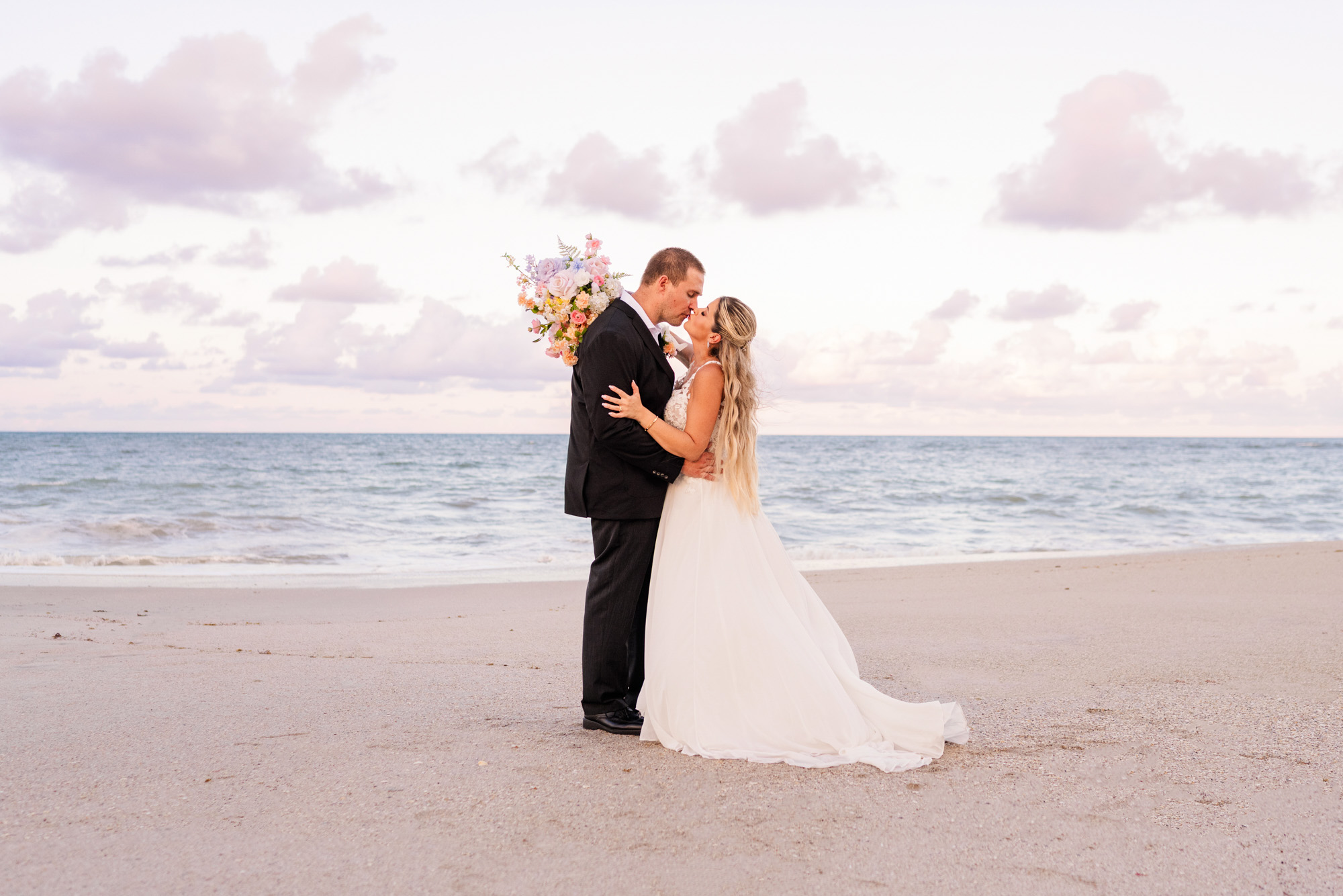 Bride and groom kissing on the beach during their Costa d’Este wedding in Vero Beach, Florida.