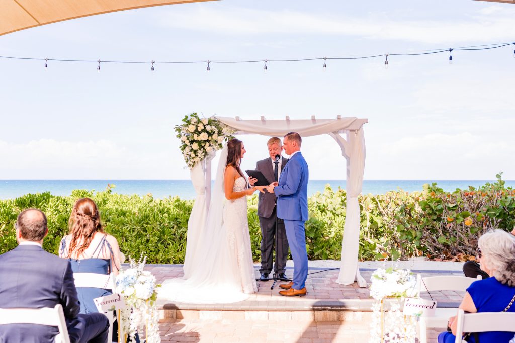 Couple saying vows under arch at Melbourne Beach Oceanfront elopement ceremony