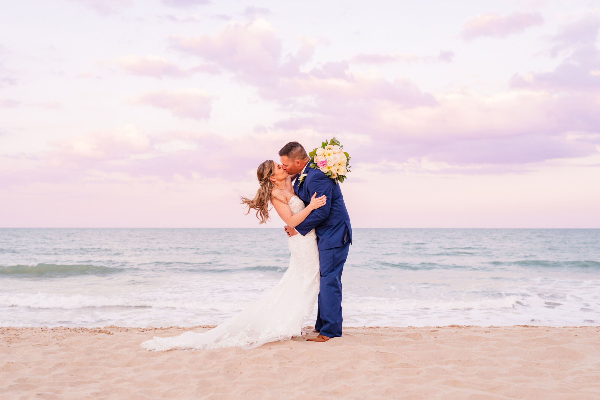 Couple hugging on the beach with a beautiful sunset after their elopement at Harbour House Oceanfront Venue