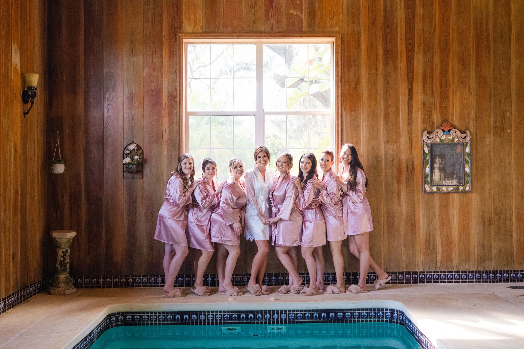 Bride and bridesmaids posing together beside the indoor pool at Estate on the Halifax.