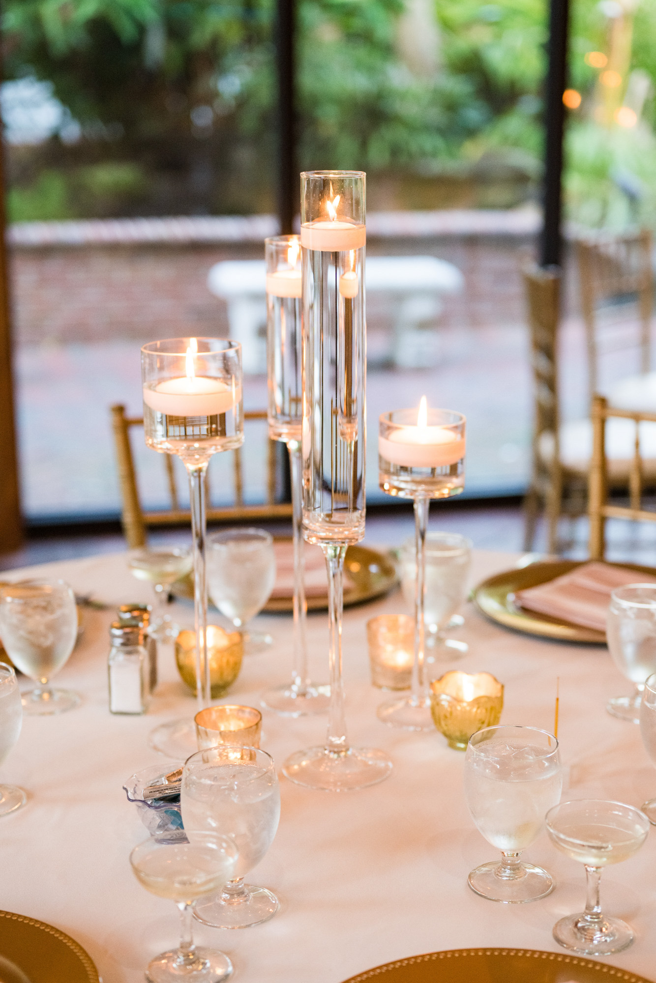 Floating candles and gold place settings decorating a reception table at Estate on the Halifax.
