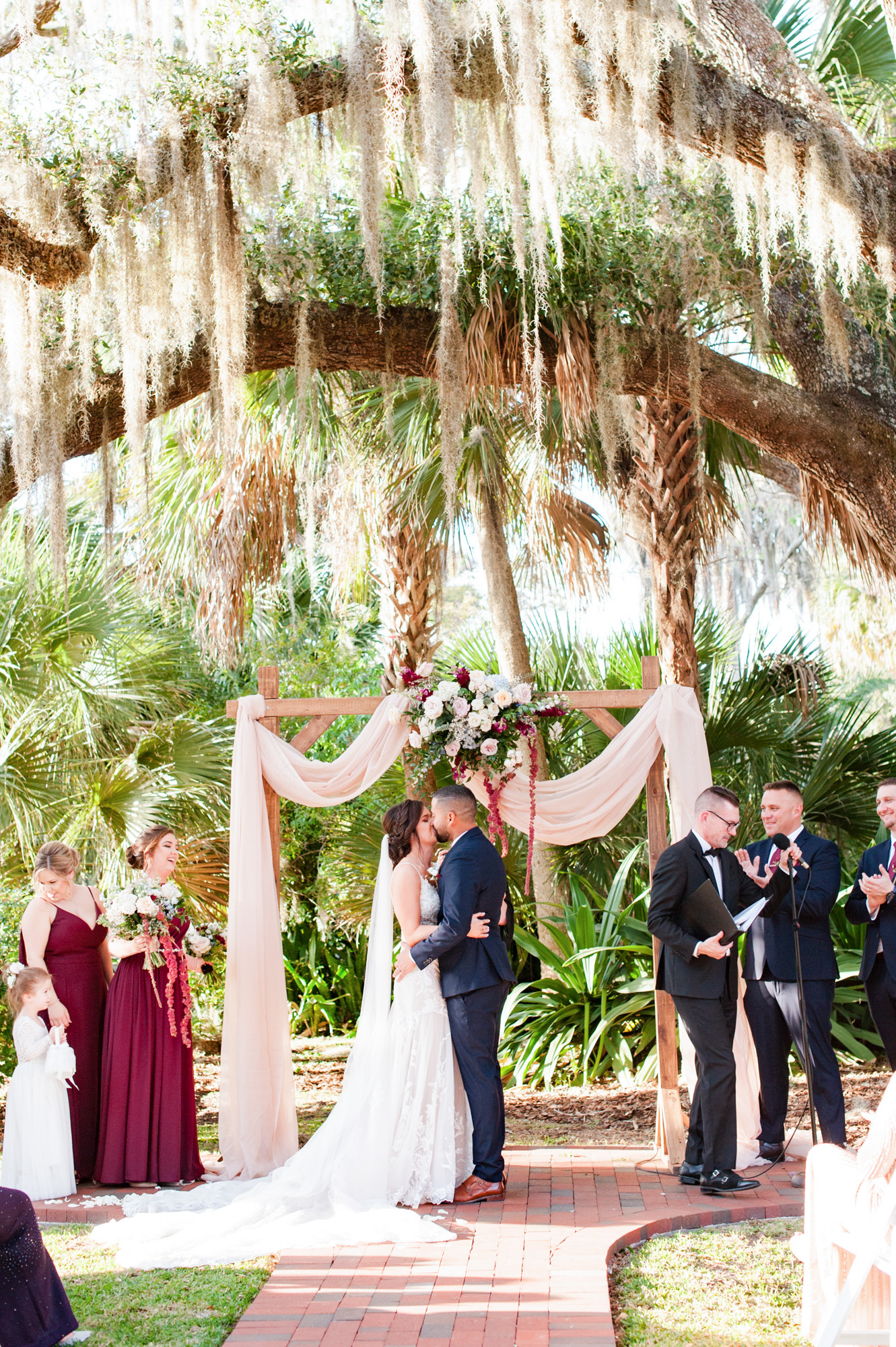 Bride and groom sharing their first kiss beneath the ceremony arch and Spanish moss.
