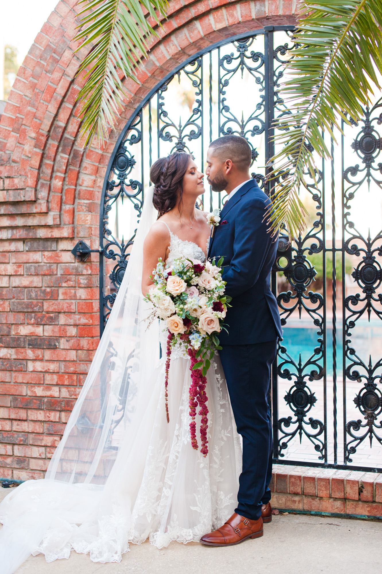 Bride and groom posing together beside an ornate wrought-iron gate at Estate on the Halifax.