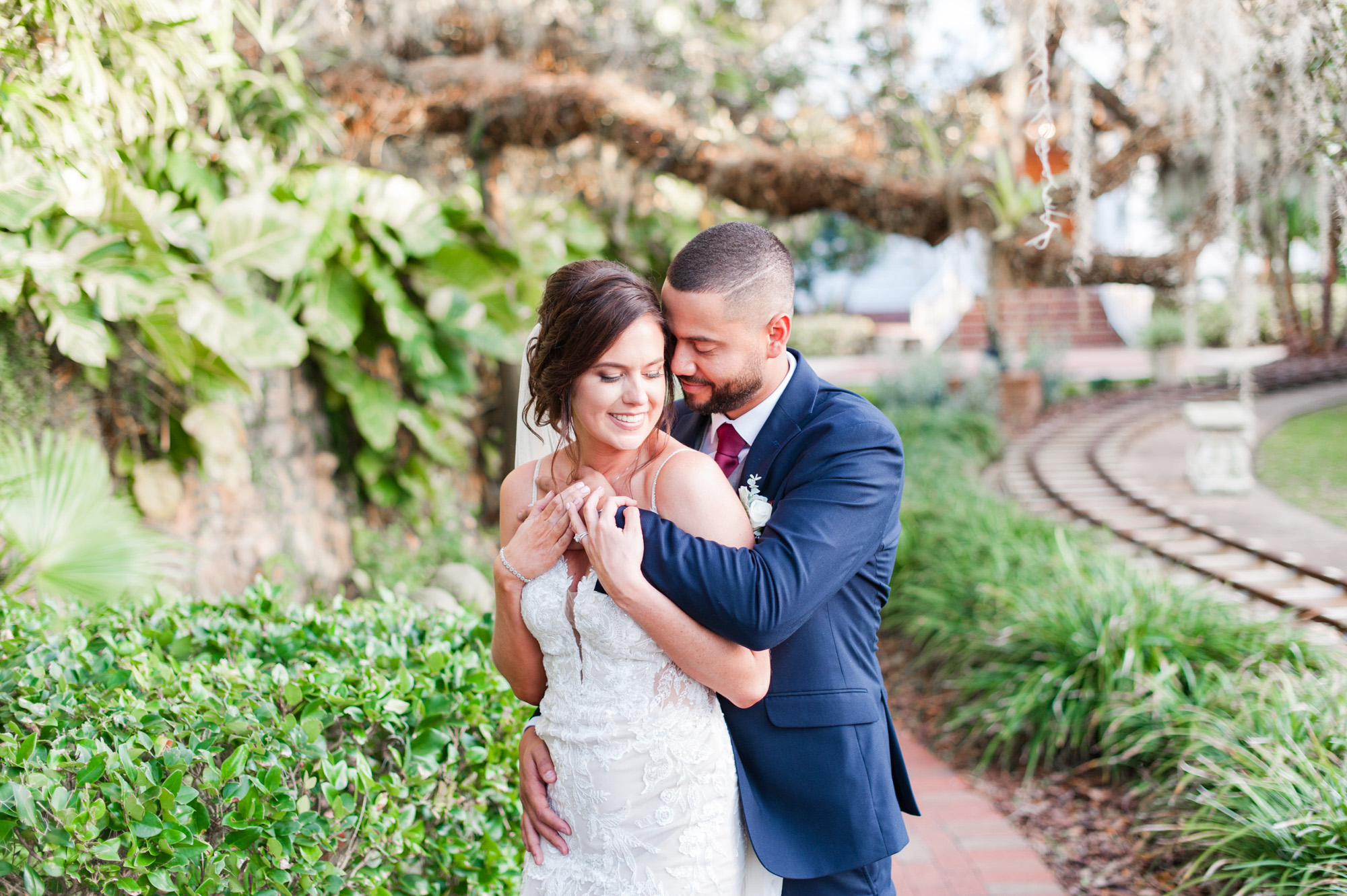 Groom embracing the bride during a quiet portrait beside the garden railway at Estate on the Halifax.