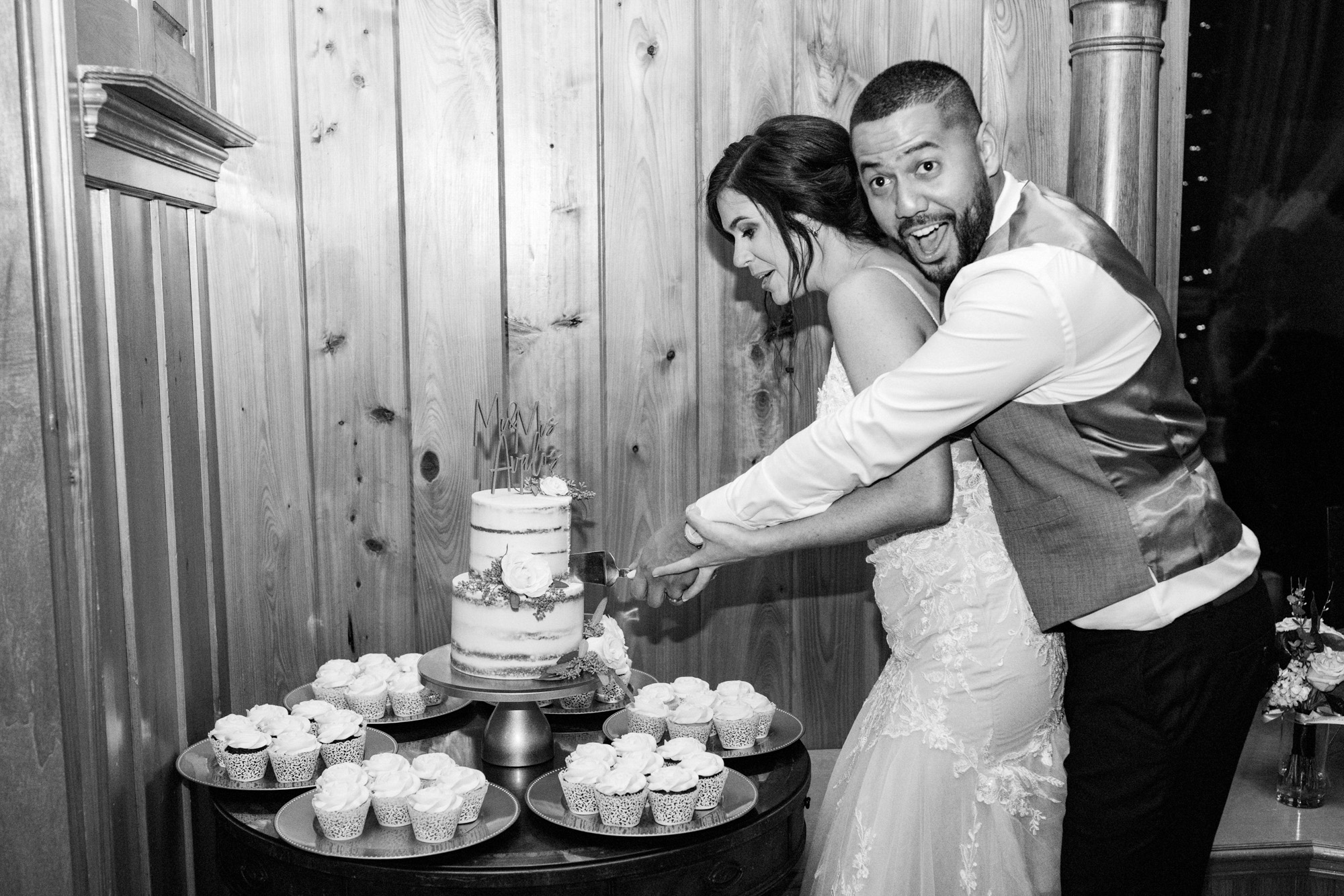 Bride and groom playfully cutting their wedding cake during the reception.