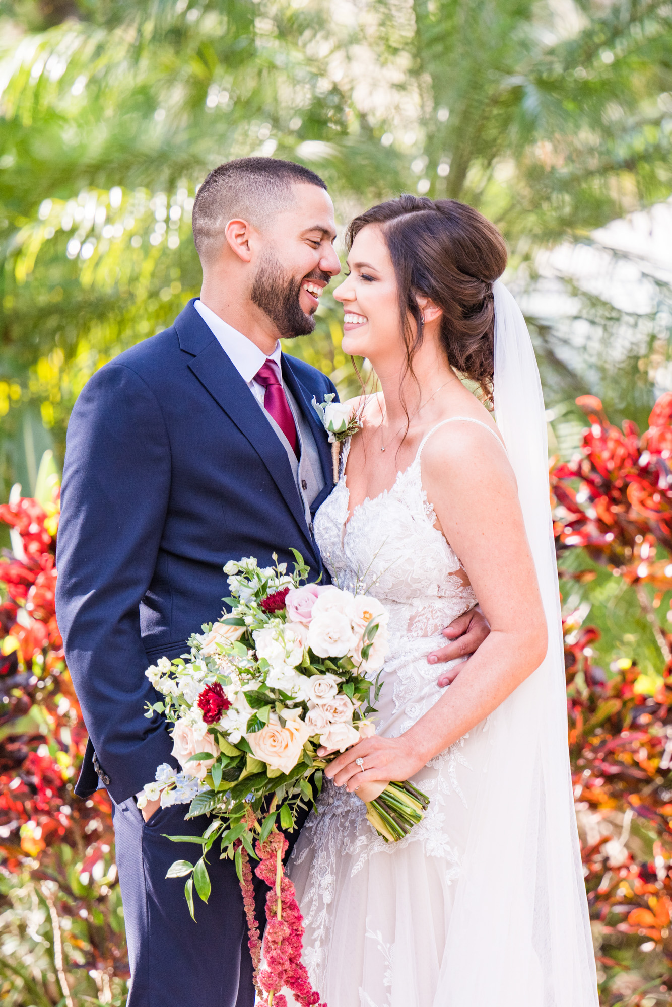 Bride and groom laughing together during their wedding portraits in the gardens.