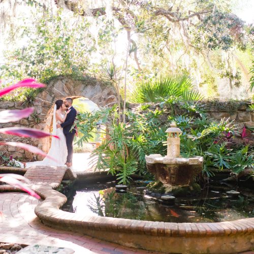 Bride and groom standing beside a garden pond and fountain at Estate on the Halifax.