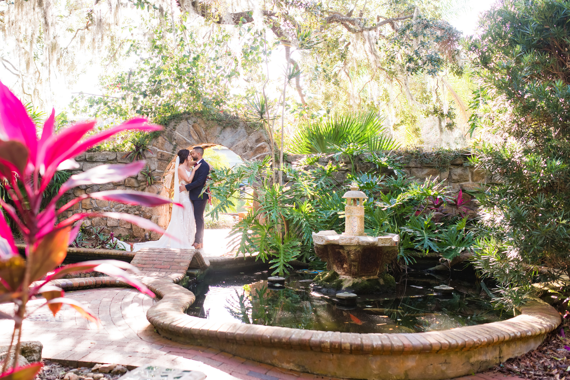 Bride and groom standing beside a garden pond and fountain at Estate on the Halifax.