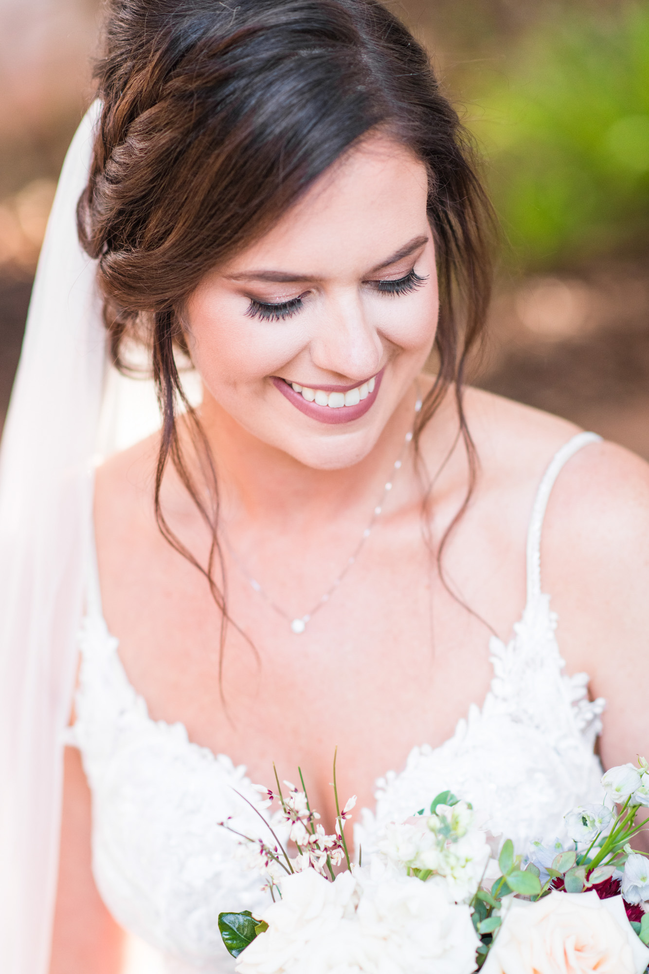 Close-up bridal portrait with the bride smiling down at her wedding bouquet.