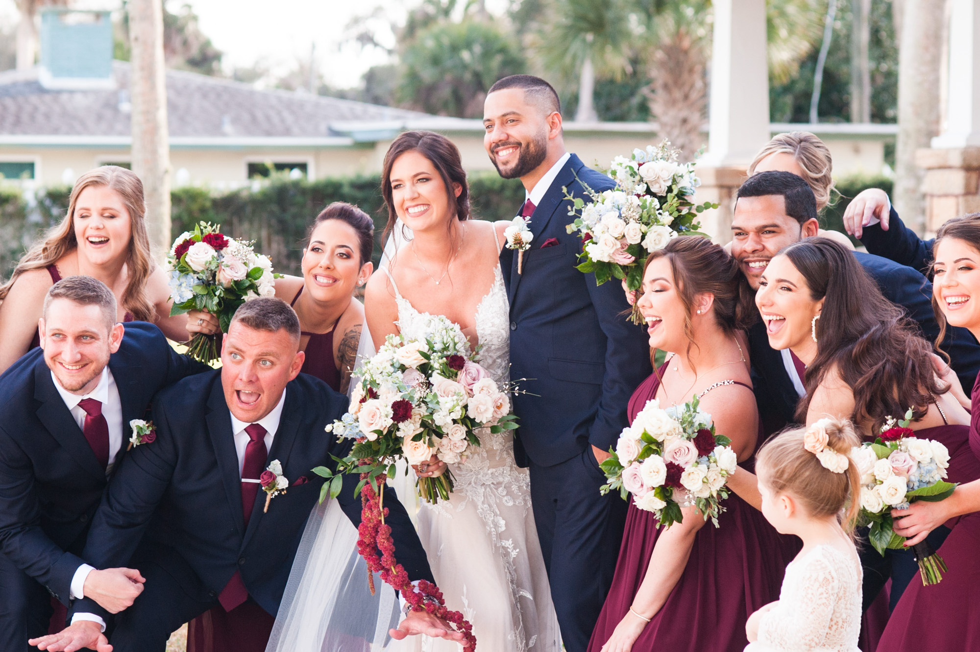 Bride and groom surrounded by their wedding party during a fun outdoor group portrait.