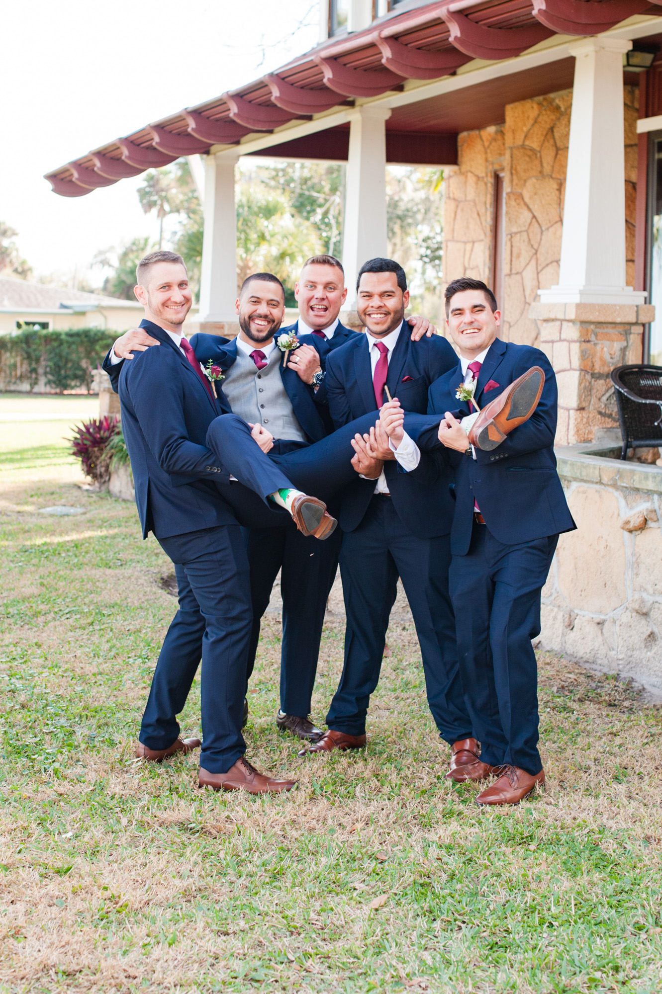 Groomsmen carrying the groom during a fun portrait outside the historic Estate on the Halifax building.