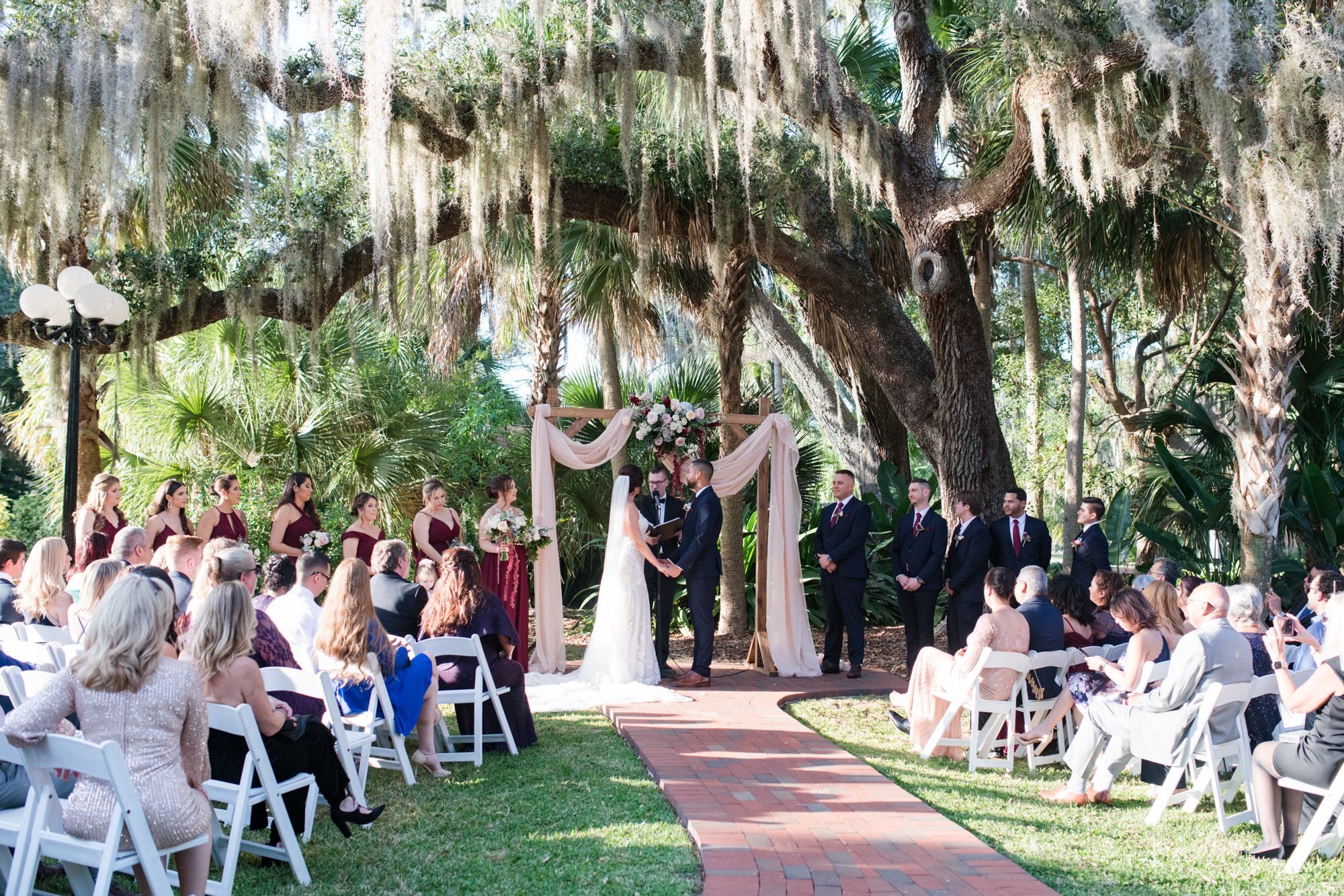 Wide view of the bride and groom exchanging vows beneath a large oak tree at Estate on the Halifax.
