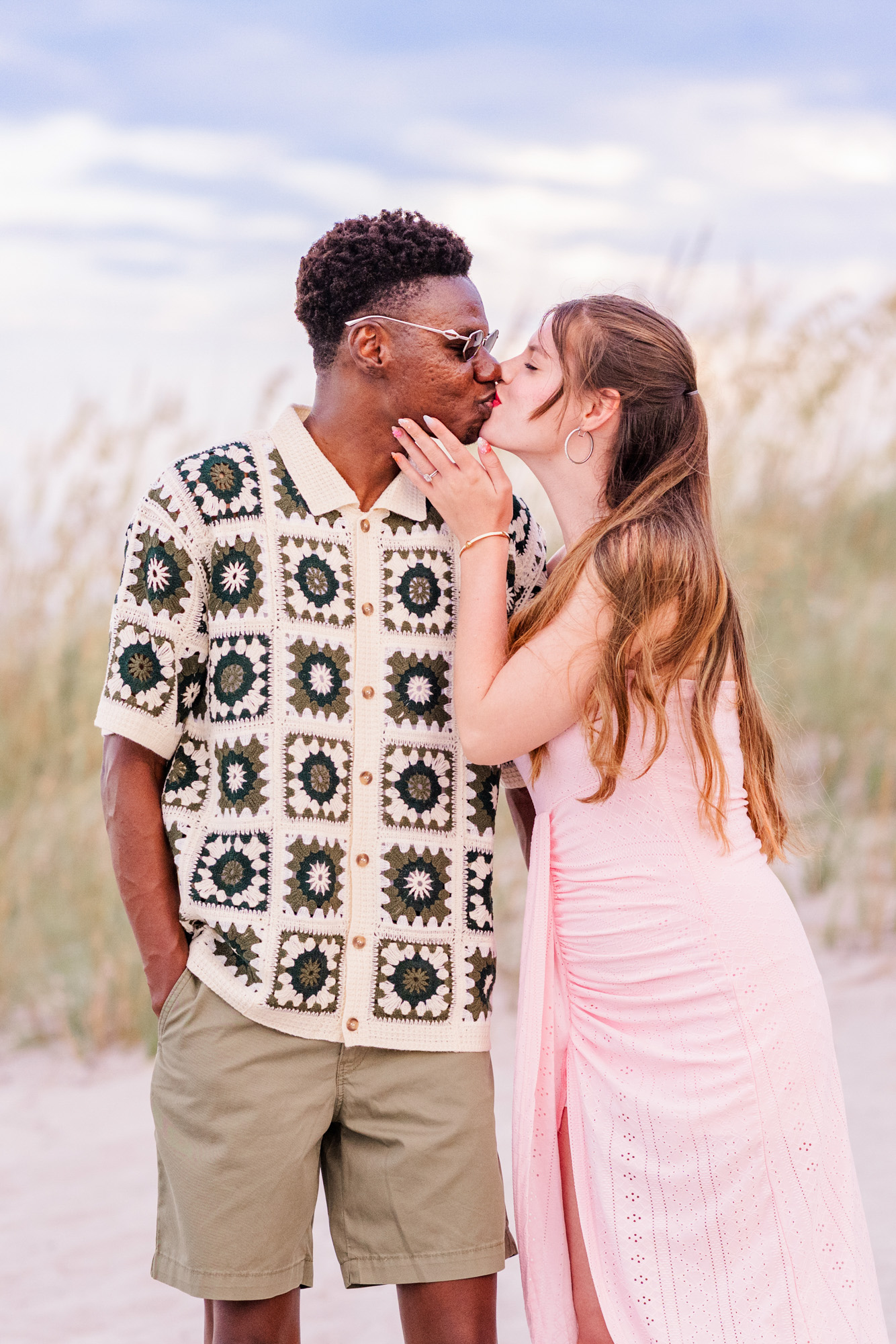 Girl in pink kissing a man by the dunes