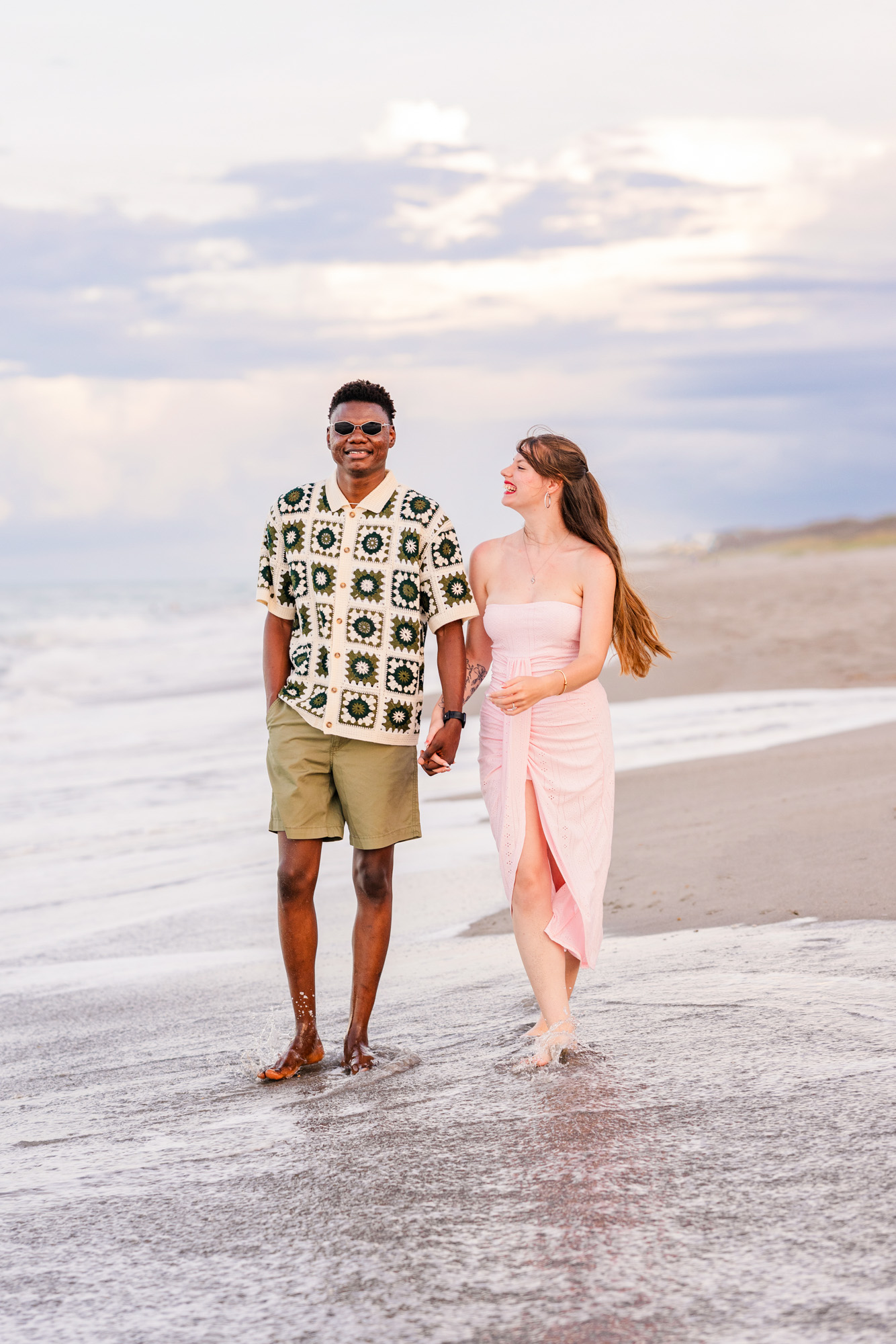 Couple holding hands walking down the beach