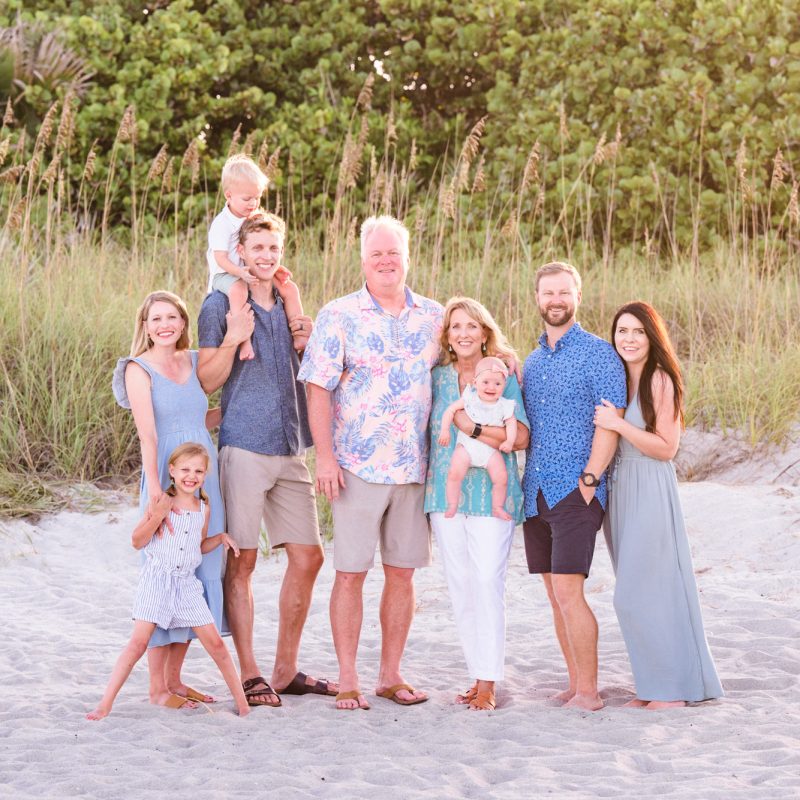 An extended family in coordinating outfits with the dunes in the background