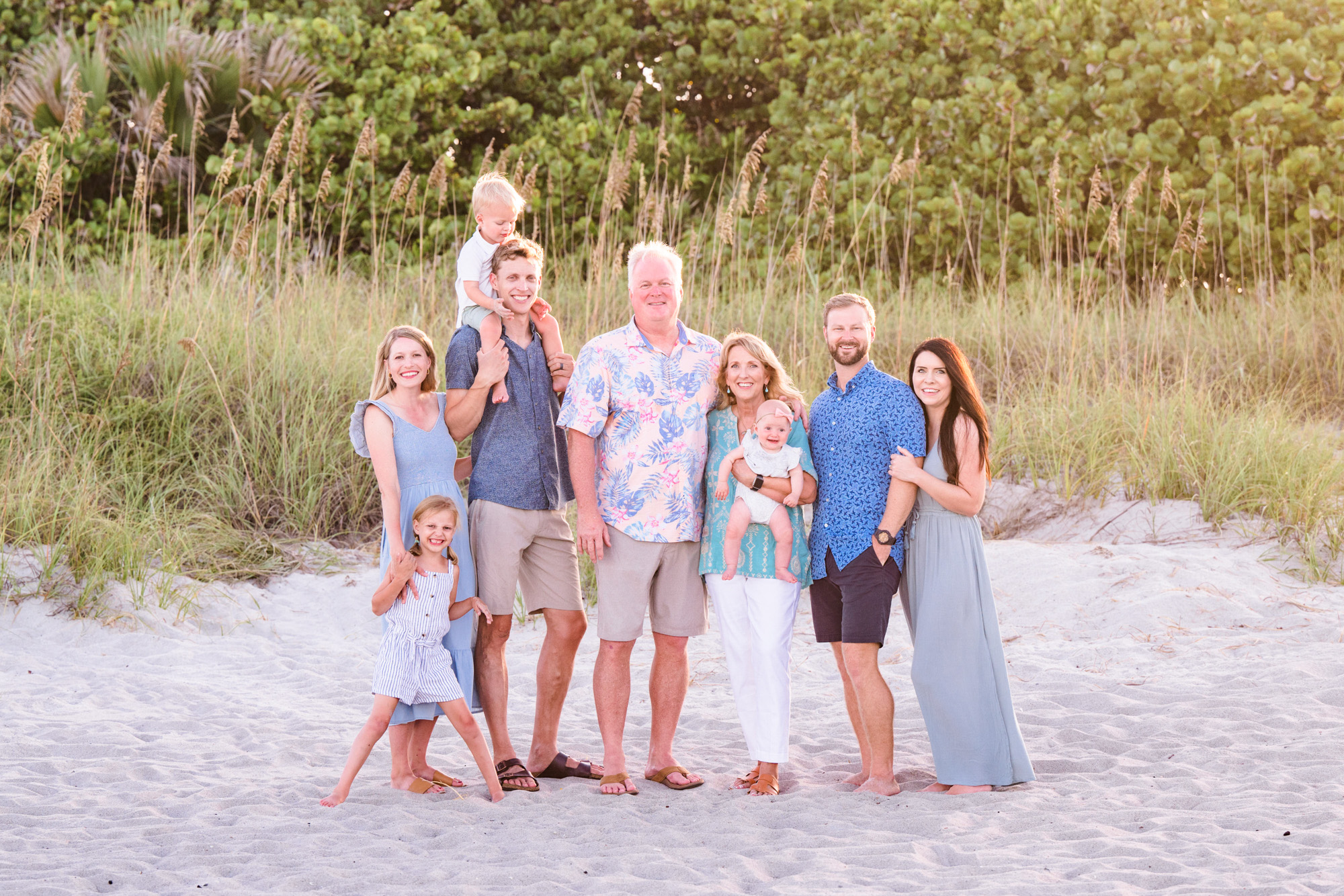 An extended family in coordinating outfits with the dunes in the background