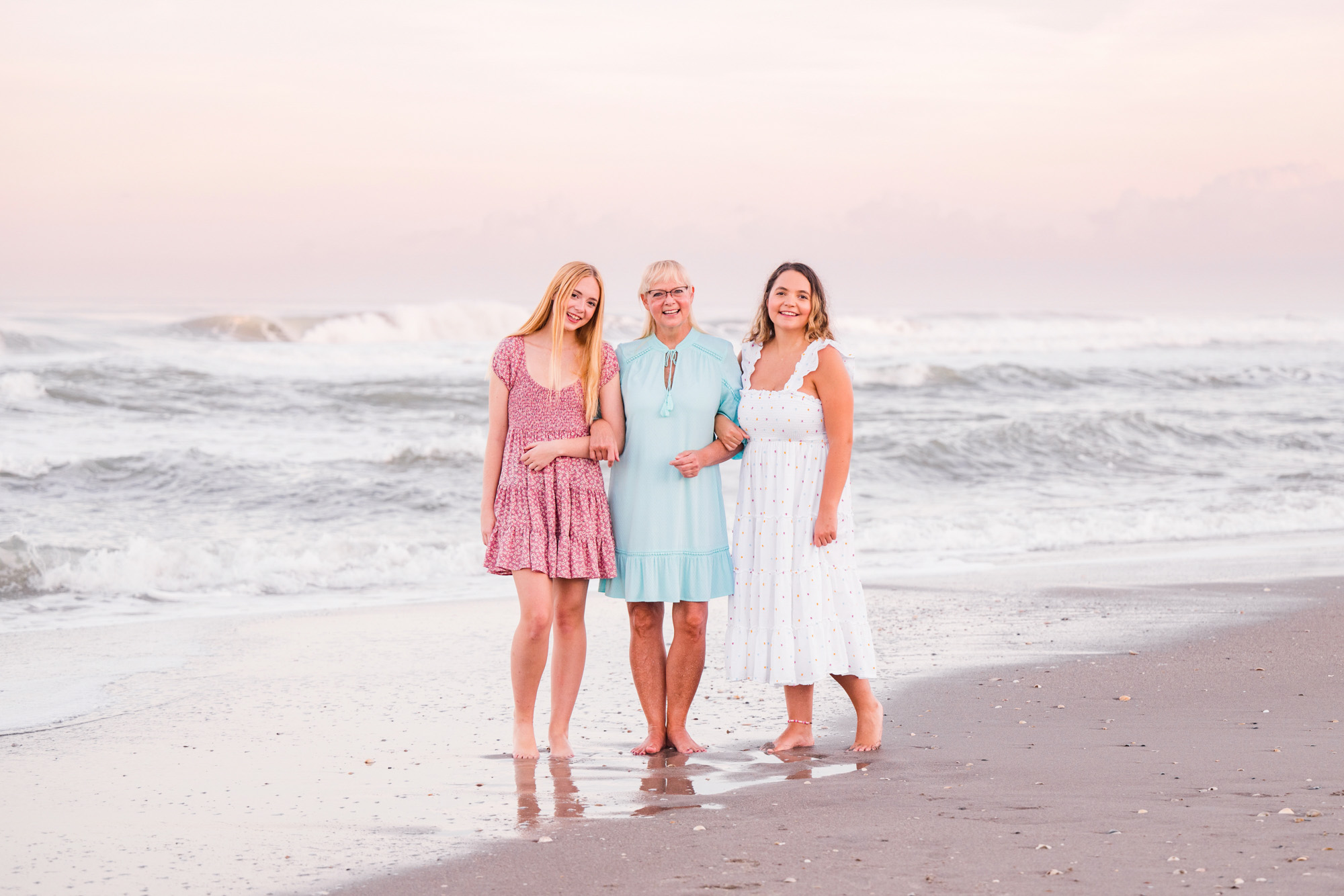 Two daughters with their mom dressed in pastel short dresses