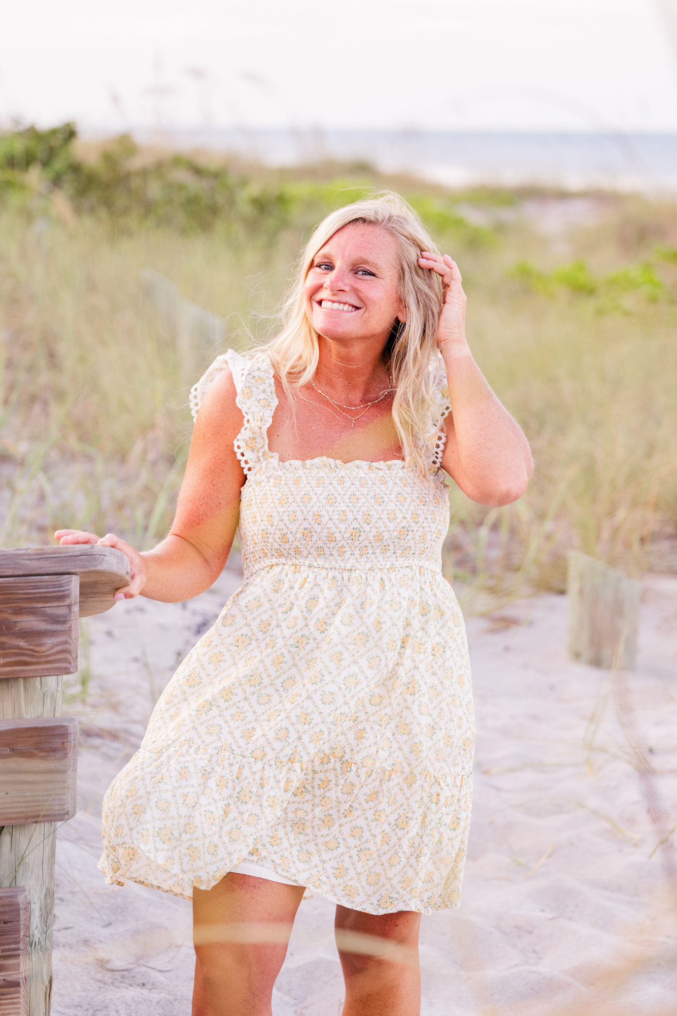 woman in white short dress holding hair on a windy day