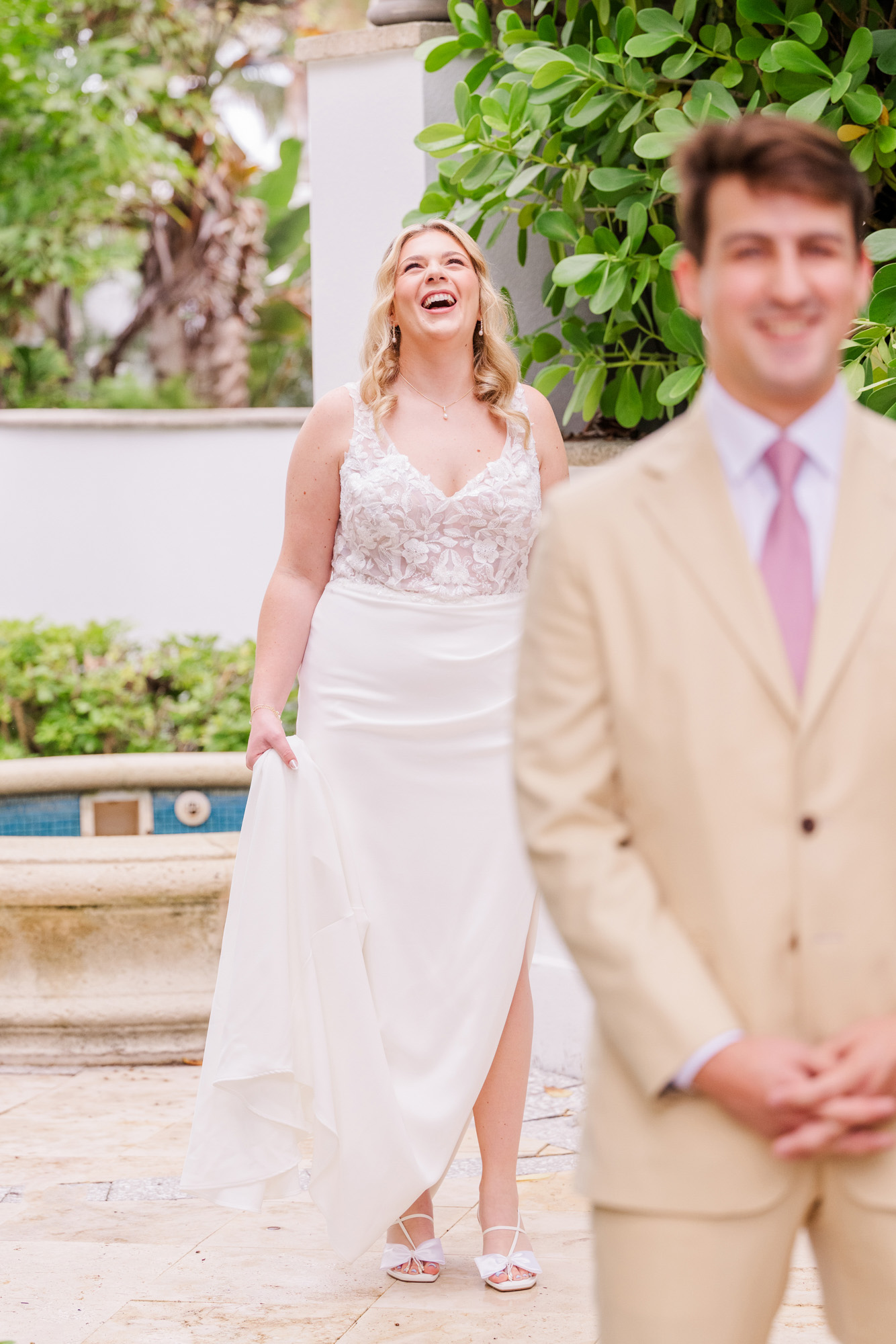 Bride laughs behind the groom moments before their wedding first look.