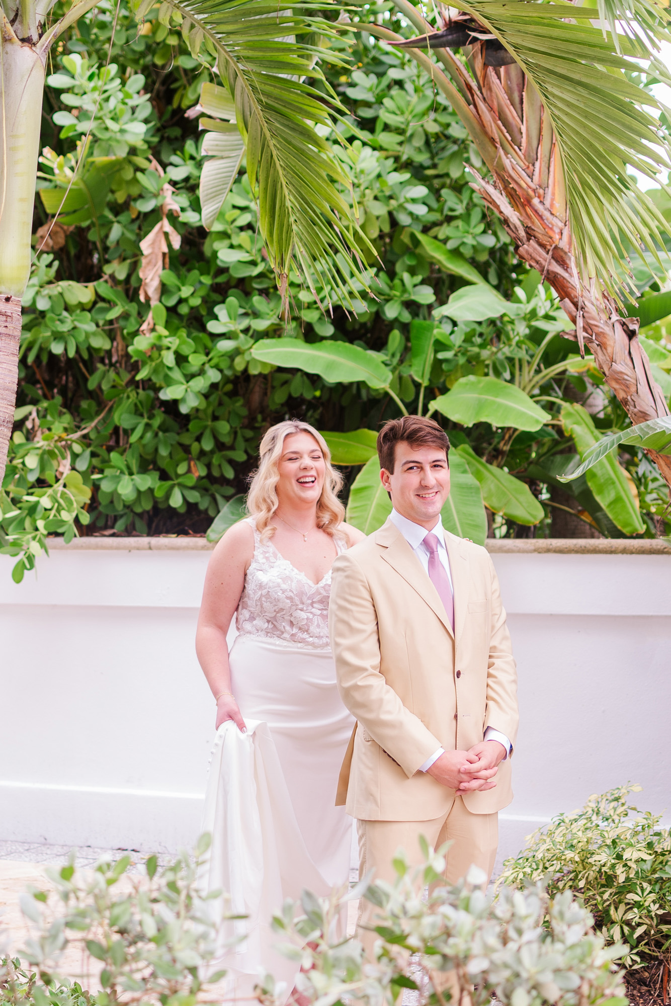 Bride and groom laugh together during their wedding first look in a tropical garden at Vero Beach Hotel and Spa.