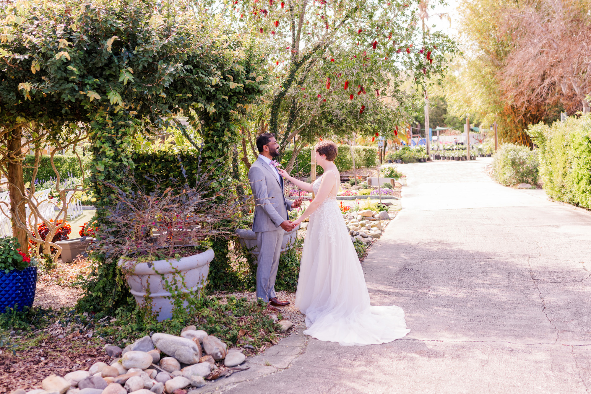 Bride and groom hold hands and smile at each other during a garden wedding first look.