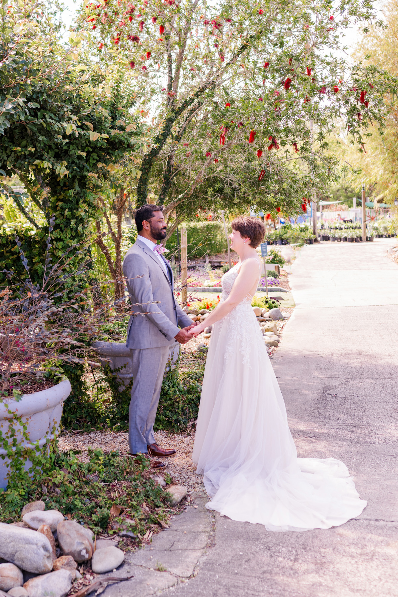 Bride and groom share their first look beneath flowering trees in a garden setting.